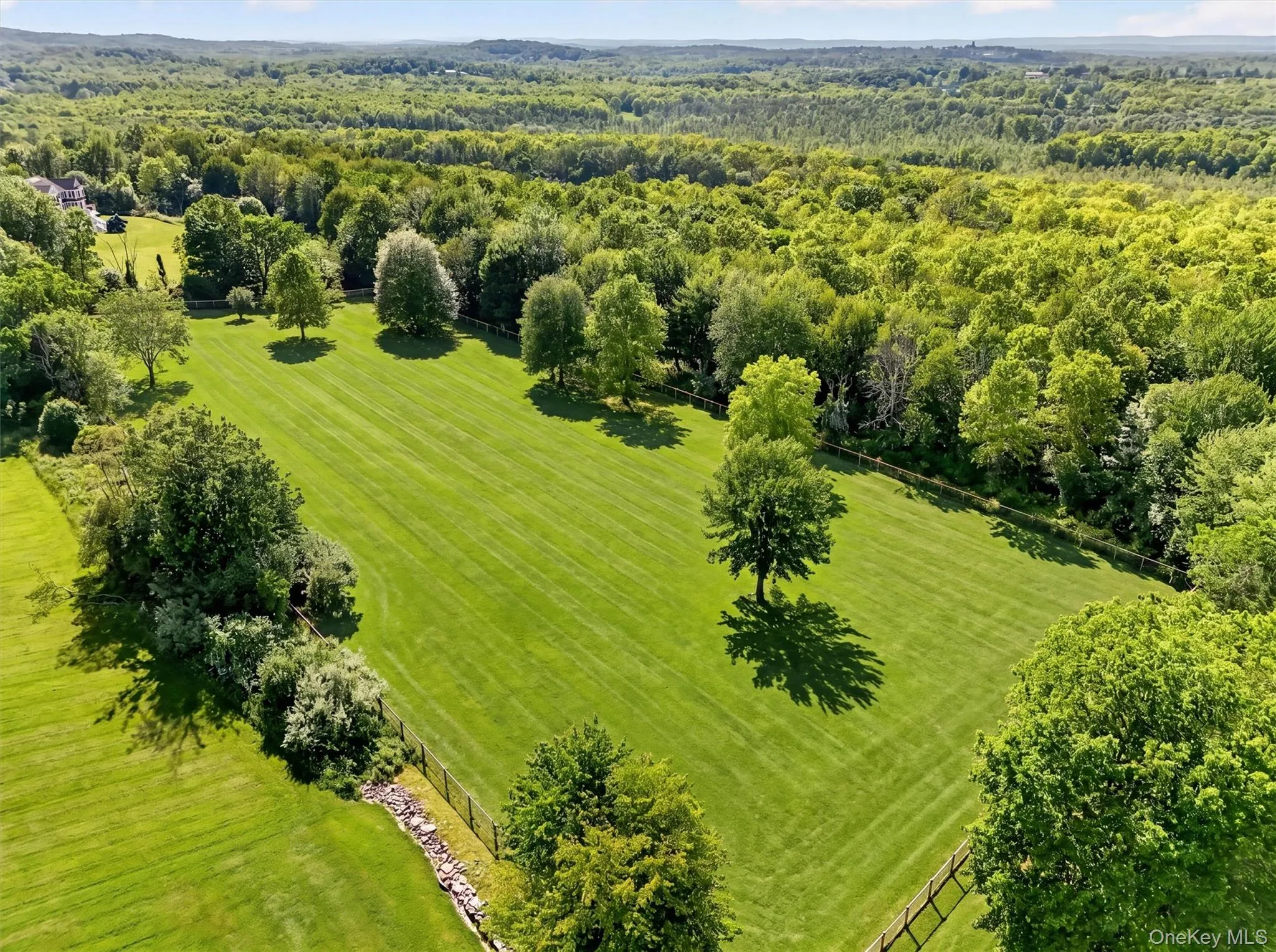 Beyond this large, fenced field is the wooded part of the property for trail riding, hiking, or additional fields or infrastructure Beyond this large, fenced field is the wooded part of the property for trail riding, hiking, or additional fields or infrastructure