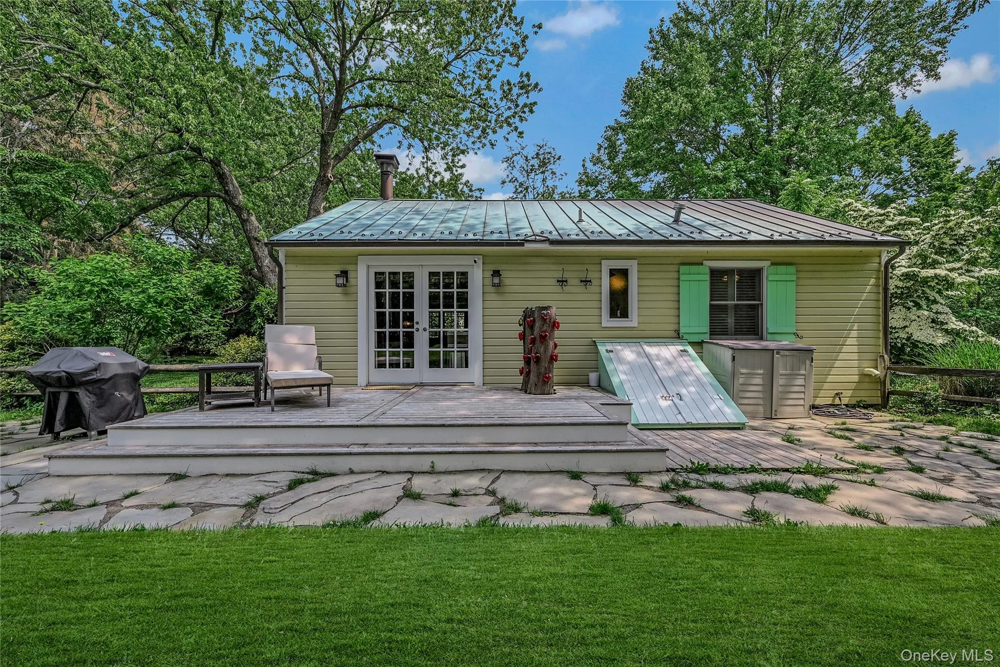 Back of house with french doors, a standing seam roof, a deck, a metal roof, and a yard Back of house with french doors, a standing seam roof, a deck, a metal roof, and a yard