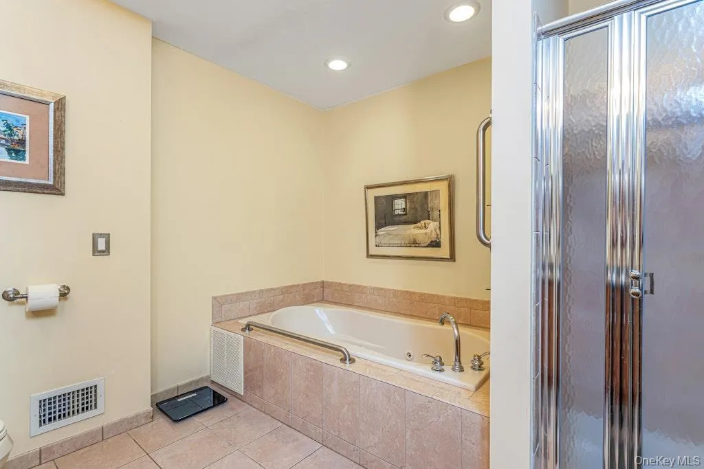 On the opposite side of the bathroom, you have a Jacuzzi tub and a stall shower with glass doors. On the opposite side of the bathroom, you have a Jacuzzi tub and a stall shower with glass doors.