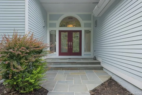 Exterior facade featuring light blue horizontal siding, a flagstone walkway, and flagstone steps leading to a dual red entry door with sidelights and an arched transom window Exterior facade featuring light blue horizontal siding, a flagstone walkway, and flagstone steps leading to a dual red entry door with sidelights and an arched transom window