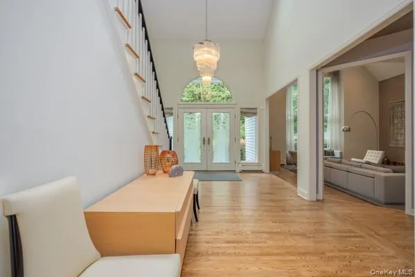 Two-story foyer featuring hardwood flooring, a prominent staircase with white risers and wood treads, a vaulted ceiling, and an arched transom window above the double entry doors Two-story foyer featuring hardwood flooring, a prominent staircase with white risers and wood treads, a vaulted ceiling, and an arched transom window above the double entry doors