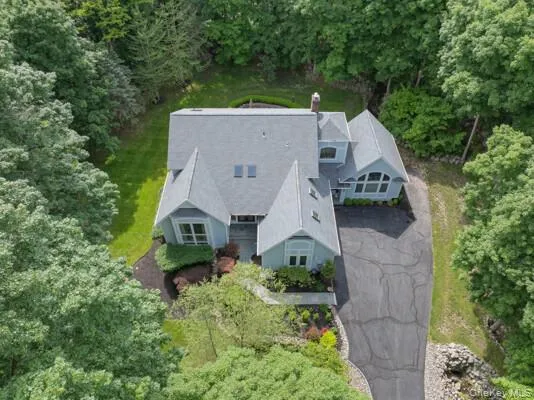 Expansive property featuring a multi-gabled roofline, light blue siding, and abundant surrounding greenery Expansive property featuring a multi-gabled roofline, light blue siding, and abundant surrounding greenery