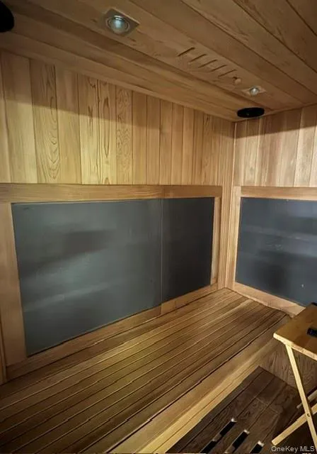 Custom sauna featuring wood paneling throughout, built-in wooden benches, recessed ceiling lighting, and integrated dark panel heating elements Custom sauna featuring wood paneling throughout, built-in wooden benches, recessed ceiling lighting, and integrated dark panel heating elements