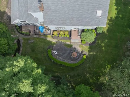 Expansive backyard featuring a stone patio surrounded by a low stone wall and manicured hedges Expansive backyard featuring a stone patio surrounded by a low stone wall and manicured hedges