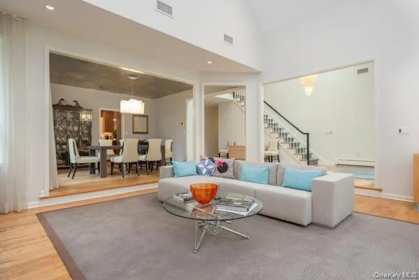 Vaulted living room featuring light wood-finish flooring, a contemporary rug, and recessed lighting Vaulted living room featuring light wood-finish flooring, a contemporary rug, and recessed lighting