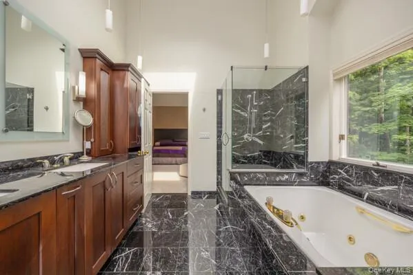 Bathroom featuring dark wood cabinetry, dual sinks, black veined stone countertops, and black veined stone flooring Bathroom featuring dark wood cabinetry, dual sinks, black veined stone countertops, and black veined stone flooring