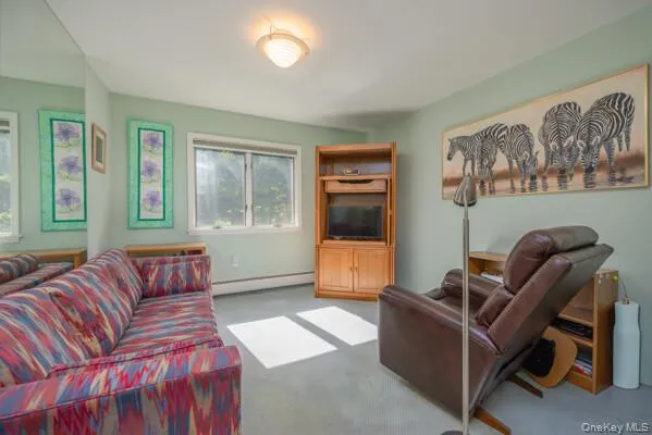 Inviting interior space featuring light green walls, a wall-mounted mirror, and carpet flooring Inviting interior space featuring light green walls, a wall-mounted mirror, and carpet flooring