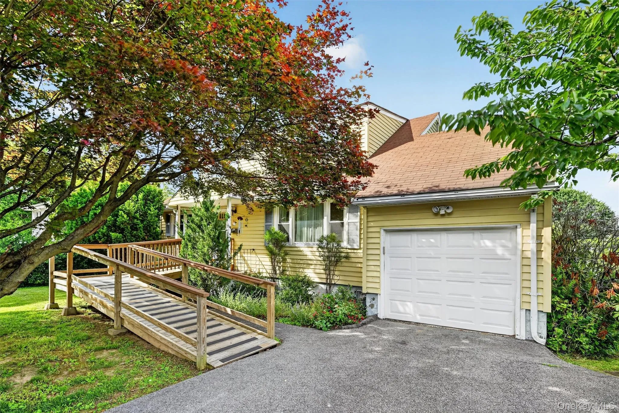 Yellow siding exterior with white trim, featuring an attached garage with a white panel door Yellow siding exterior with white trim, featuring an attached garage with a white panel door