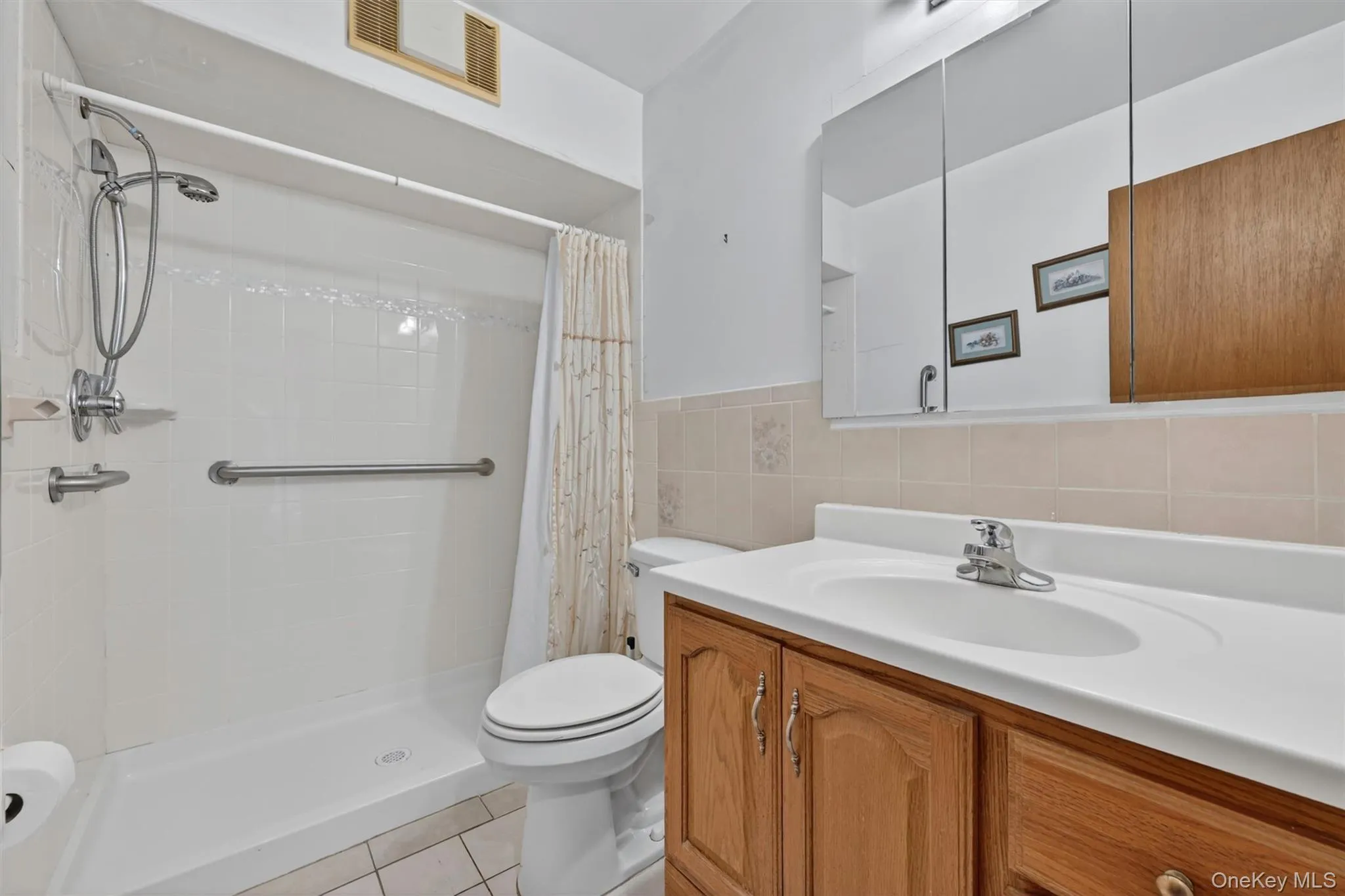 Bathroom featuring a wood-finish vanity with an integrated sink and chrome faucet, walk in shower Bathroom featuring a wood-finish vanity with an integrated sink and chrome faucet, walk in shower