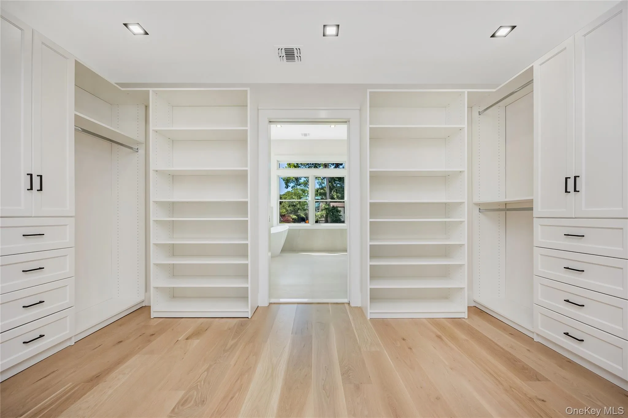 Custom walk-in closet with extensive white cabinetry and shelving Custom walk-in closet with extensive white cabinetry and shelving