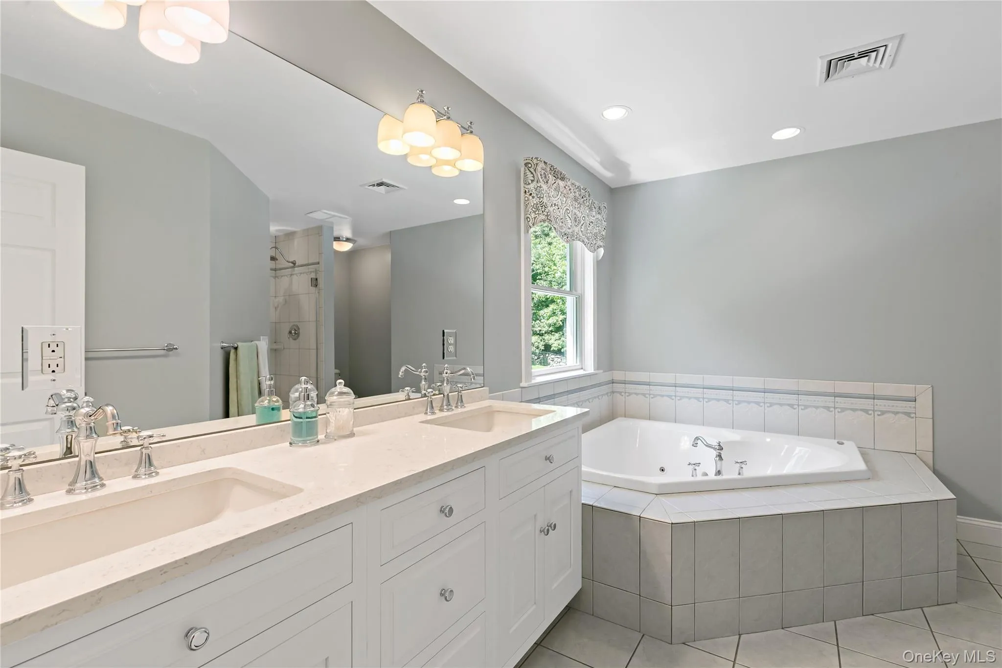 Primary bathroom with double vanity, jacuzzi tub and separate shower with glass doors. Primary bathroom with double vanity, jacuzzi tub and separate shower with glass doors.