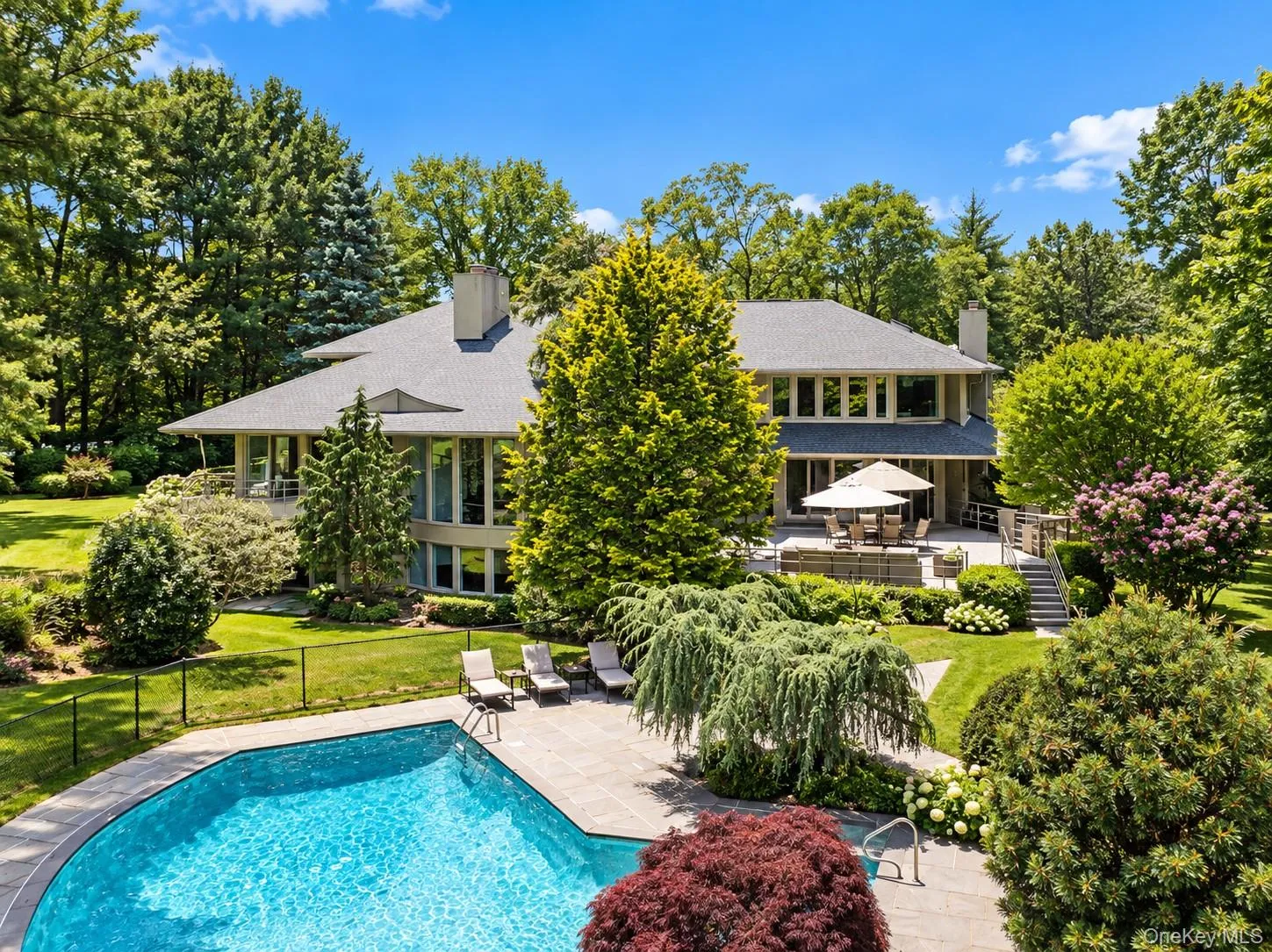 Expansive property featuring a curved swimming pool, stone patio, and multi-level decking Expansive property featuring a curved swimming pool, stone patio, and multi-level decking