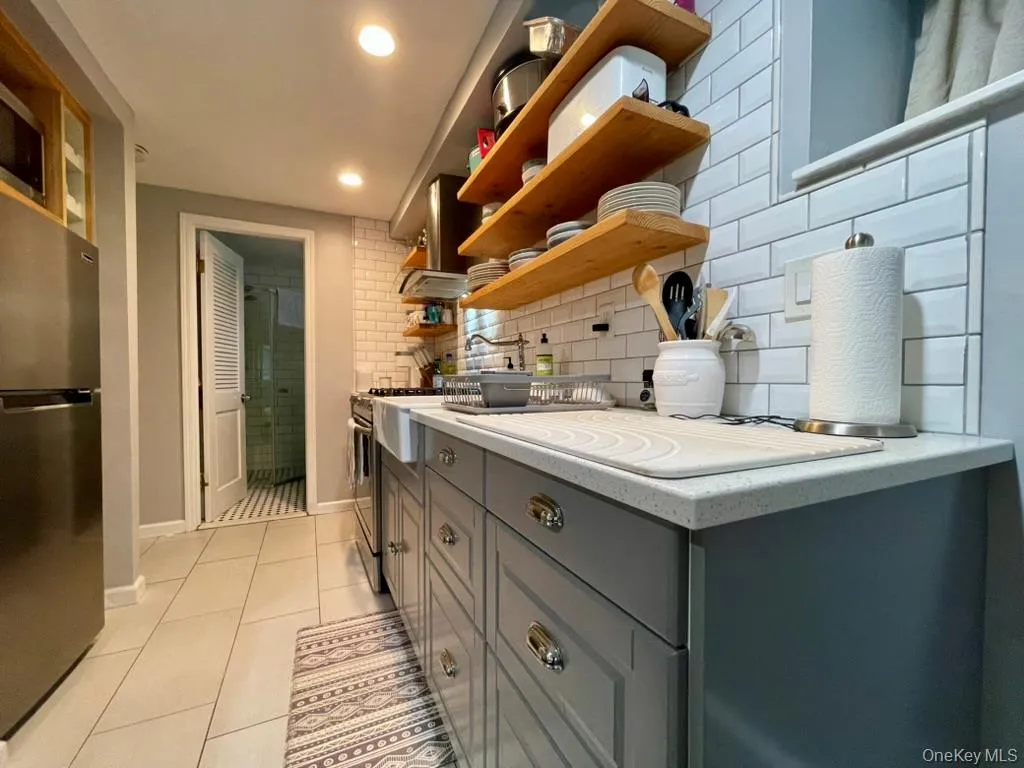 Kitchen with Quartz counters, porcelain farmhouse sink, open shelving, stainless appliances Kitchen with Quartz counters, porcelain farmhouse sink, open shelving, stainless appliances