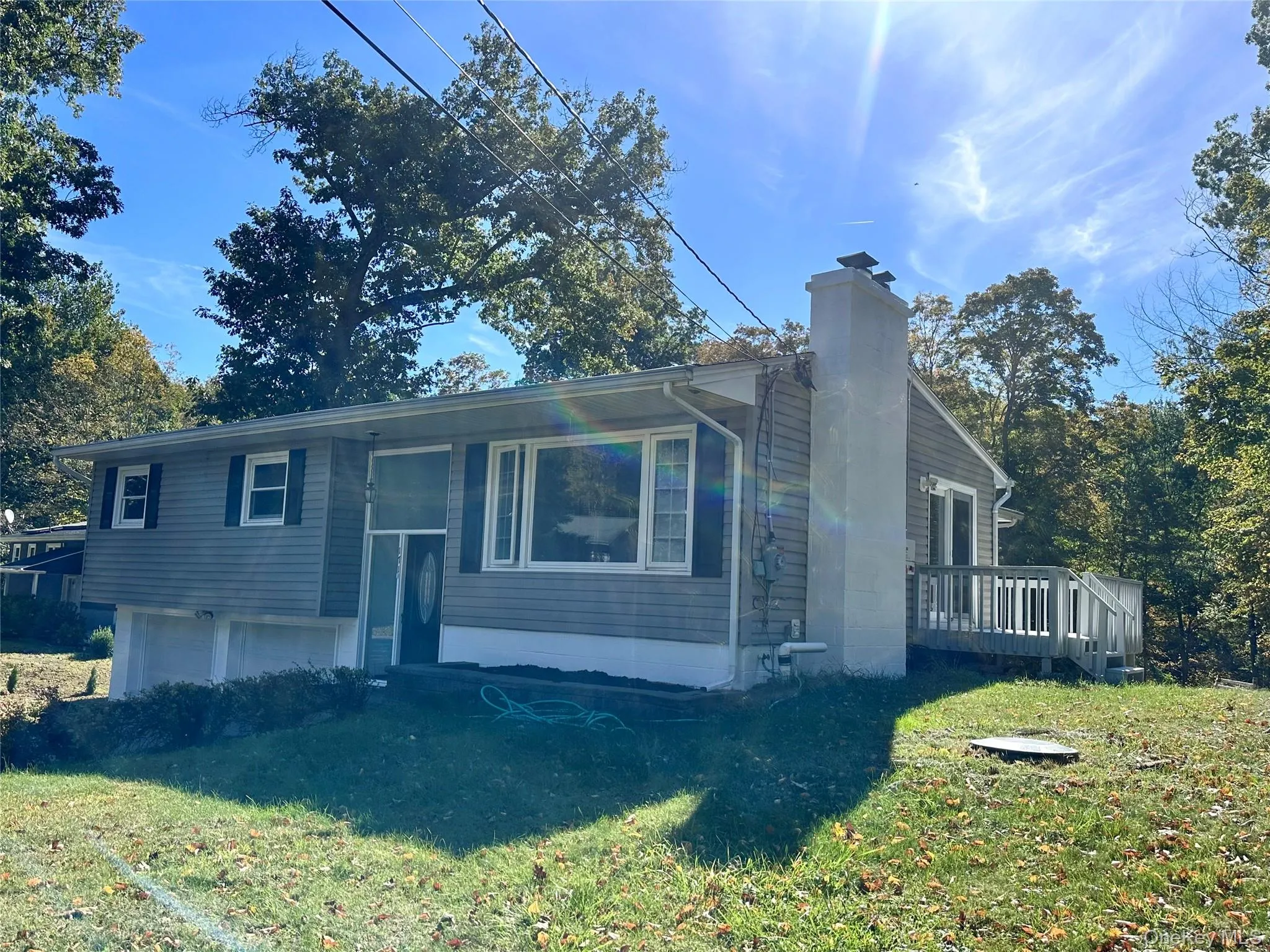 View of front of property with a chimney, a front lawn, and a deck View of front of property with a chimney, a front lawn, and a deck