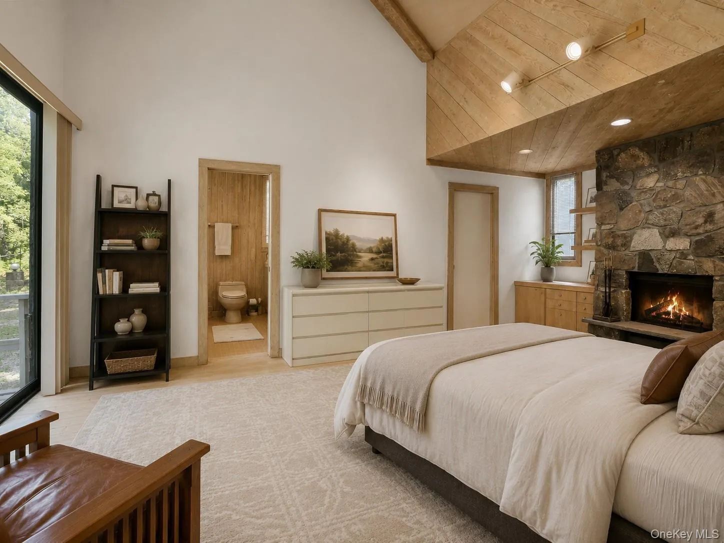 Spacious and inviting primary suite featuring soaring cathedral ceilings and a beautiful stone fireplace that adds warmth and charm. Sliding glass doors open directly to a private deck, surrounded by peaceful wooded views for a serene retreat-like feel. The suite also includes an attached primary bathroom and a generous walk-in closet area, offering both comfort and convenience. Spacious and inviting primary suite featuring soaring cathedral ceilings and a beautiful stone fireplace that adds warmth and charm. Sliding glass doors open directly to a private deck, surrounded by peaceful wooded views for a serene retreat-like feel. The suite also includes an attached primary bathroom and a generous walk-in closet area, offering both comfort and convenience.