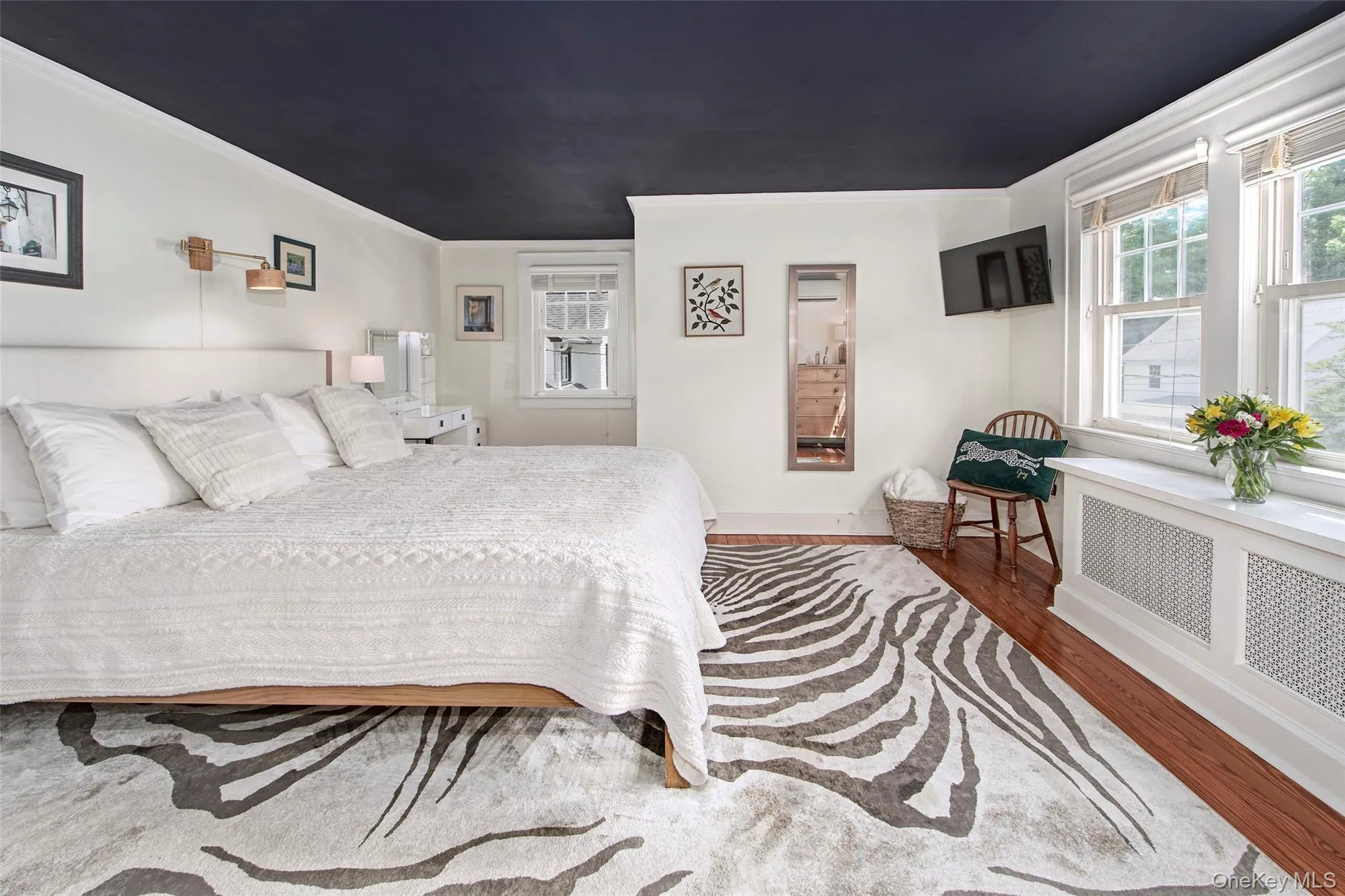 Bright and inviting primary bedroom featuring a king-size bed, multiple windows providing abundant natural light, generous closet space, and thoughtfully selected furnishings. Designed as a comfortable retreat, the space offers a peaceful setting for rest and relaxation while maintaining the warmth and character found throughout the home. Bright and inviting primary bedroom featuring a king-size bed, multiple windows providing abundant natural light, generous closet space, and thoughtfully selected furnishings. Designed as a comfortable retreat, the space offers a peaceful setting for rest and relaxation while maintaining the warmth and character found throughout the home.