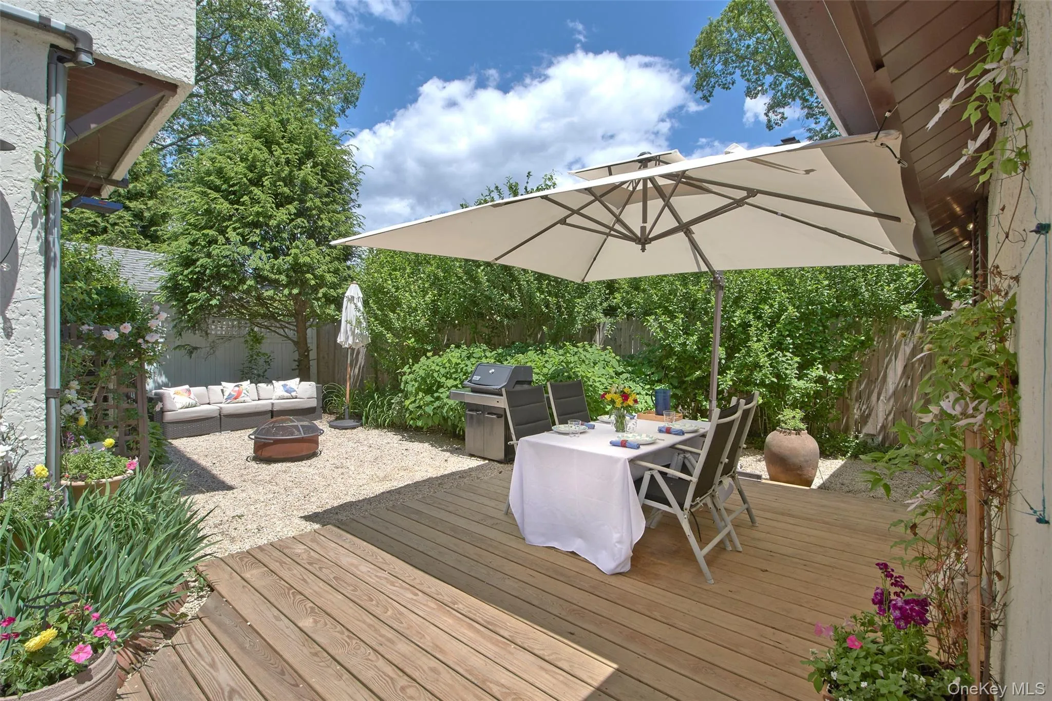 A thoughtfully designed outdoor retreat featuring a spacious deck, dining area, cantilever umbrella, fire pit, and comfortable seating surrounded by mature landscaping. Ideal for entertaining, outdoor dining, relaxing with a book, or enjoying evenings around the fire, the private backyard offers a peaceful setting for year-round enjoyment. A thoughtfully designed outdoor retreat featuring a spacious deck, dining area, cantilever umbrella, fire pit, and comfortable seating surrounded by mature landscaping. Ideal for entertaining, outdoor dining, relaxing with a book, or enjoying evenings around the fire, the private backyard offers a peaceful setting for year-round enjoyment.