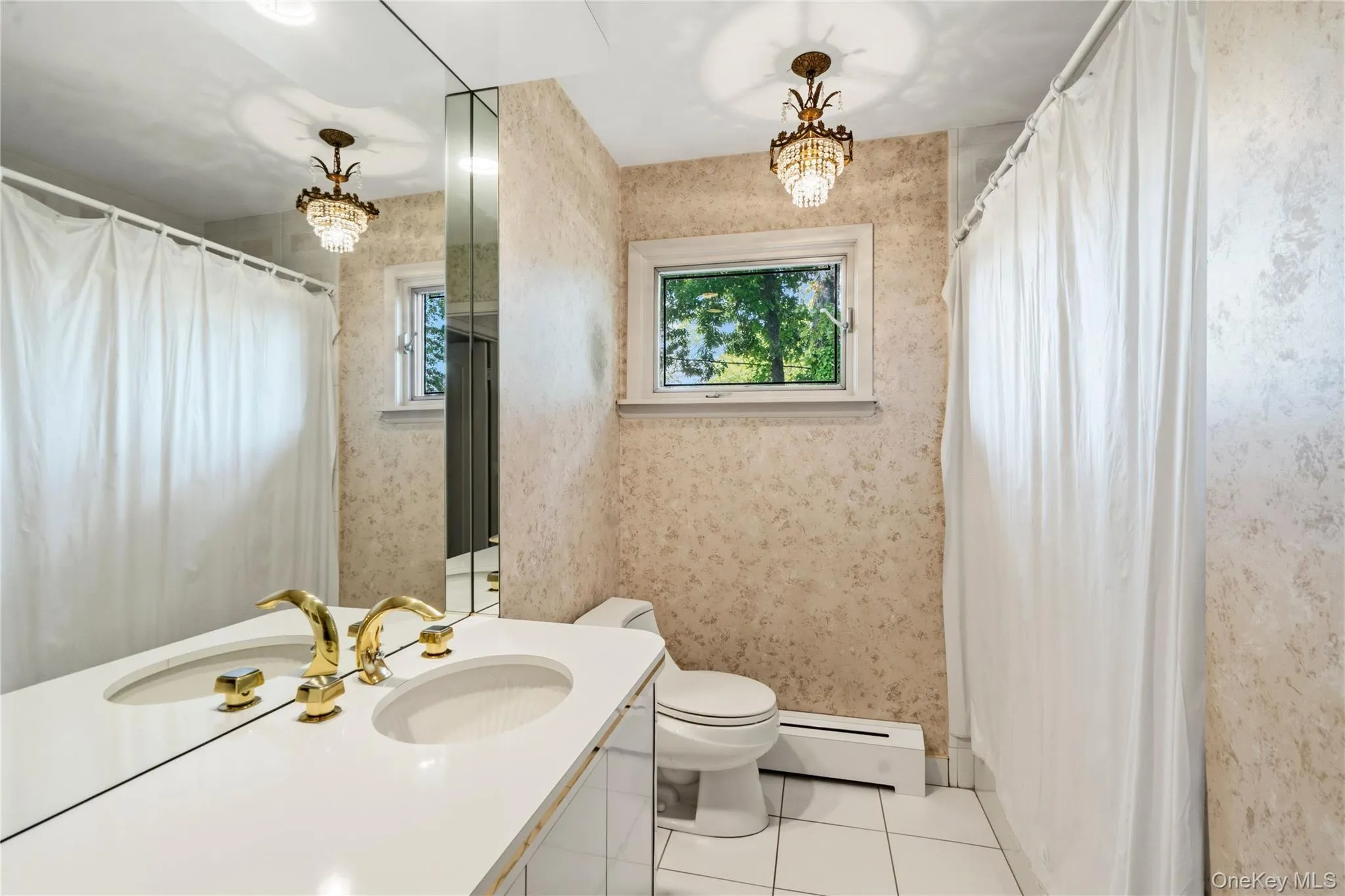 Bathroom featuring a double vanity with polished brass fixtures, recessed lighting, and a crystal chandelier Bathroom featuring a double vanity with polished brass fixtures, recessed lighting, and a crystal chandelier