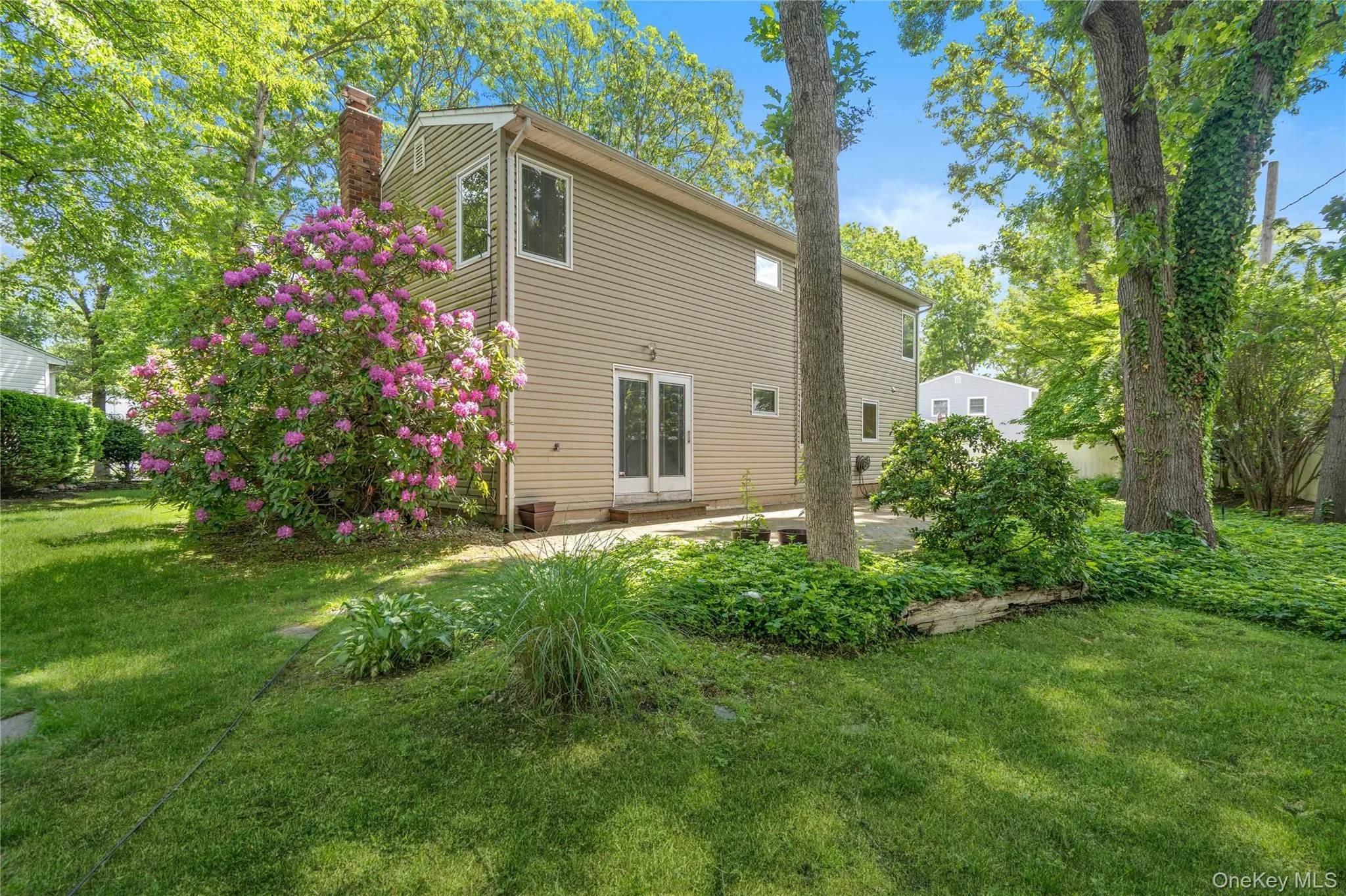 Expansive rear yard featuring mature trees, a stone patio, and speciman plantings Expansive rear yard featuring mature trees, a stone patio, and speciman plantings