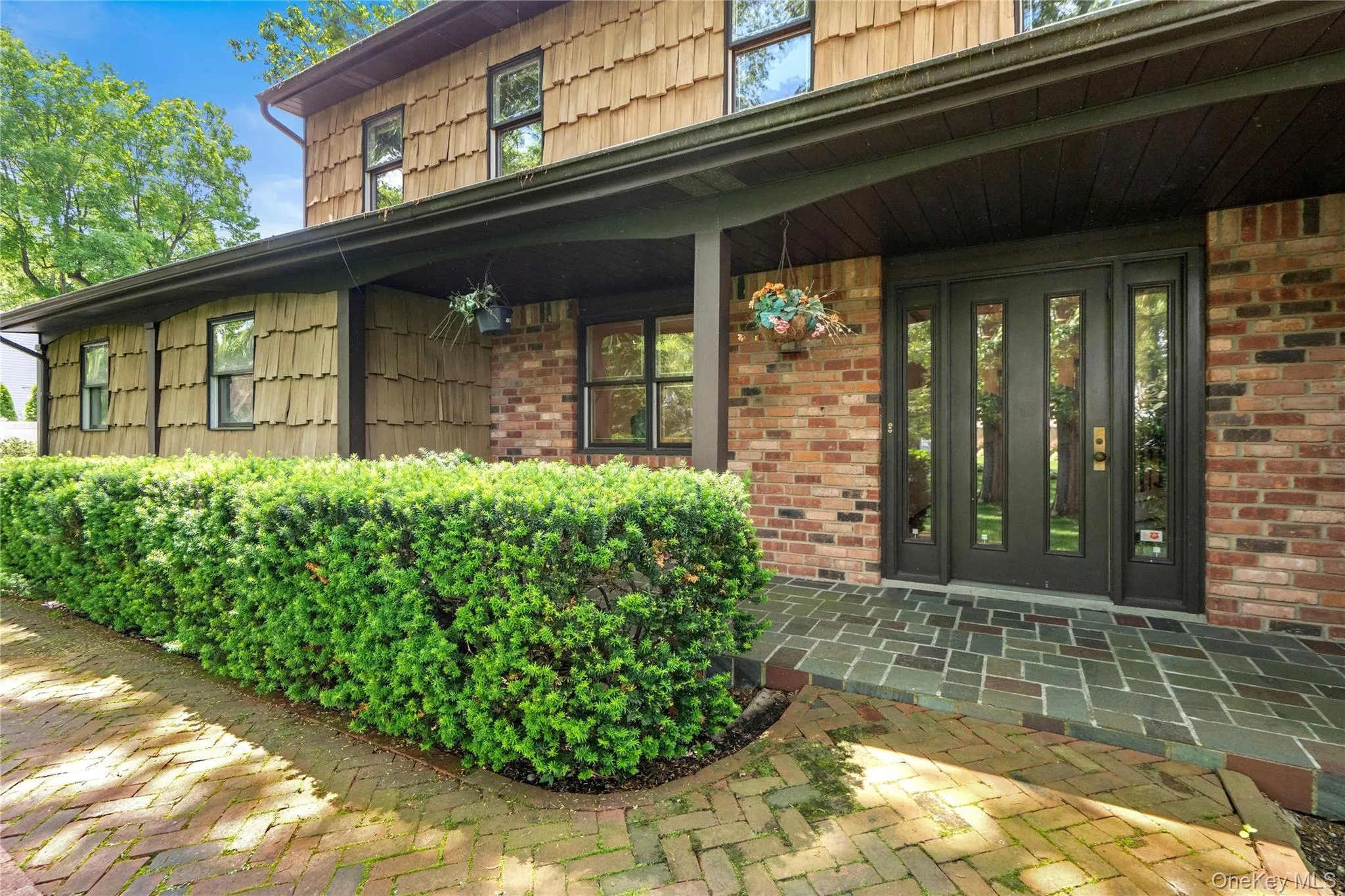 Brick and cedar shake exterior featuring a covered entry porch Brick and cedar shake exterior featuring a covered entry porch