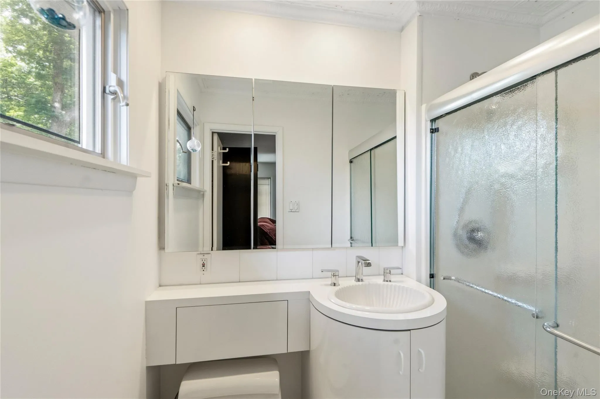 Bathroom featuring a built-in vanity with an integrated basin, a mirrored medicine cabinet, and a framed shower enclosure with textured glass Bathroom featuring a built-in vanity with an integrated basin, a mirrored medicine cabinet, and a framed shower enclosure with textured glass
