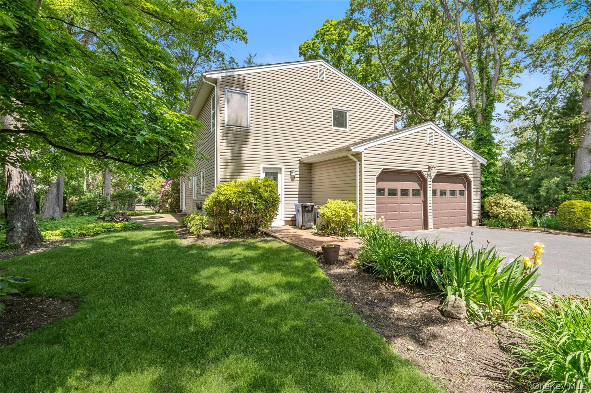 Expansive outdoor space with custom landscaping surrounding driveway and two-car garage Expansive outdoor space with custom landscaping surrounding driveway and two-car garage