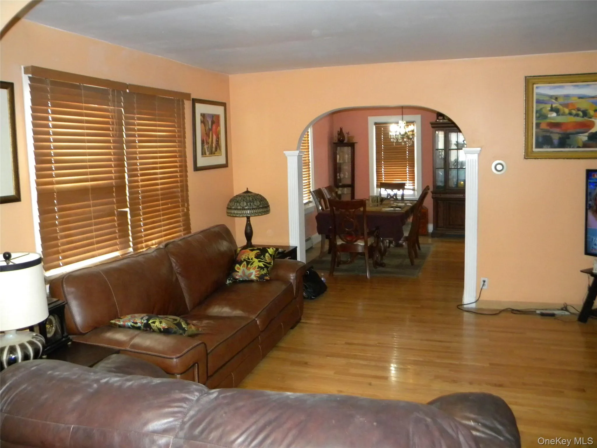 Hardwood flooring extending into an arched doorway, leading to an additional space Hardwood flooring extending into an arched doorway, leading to an additional space