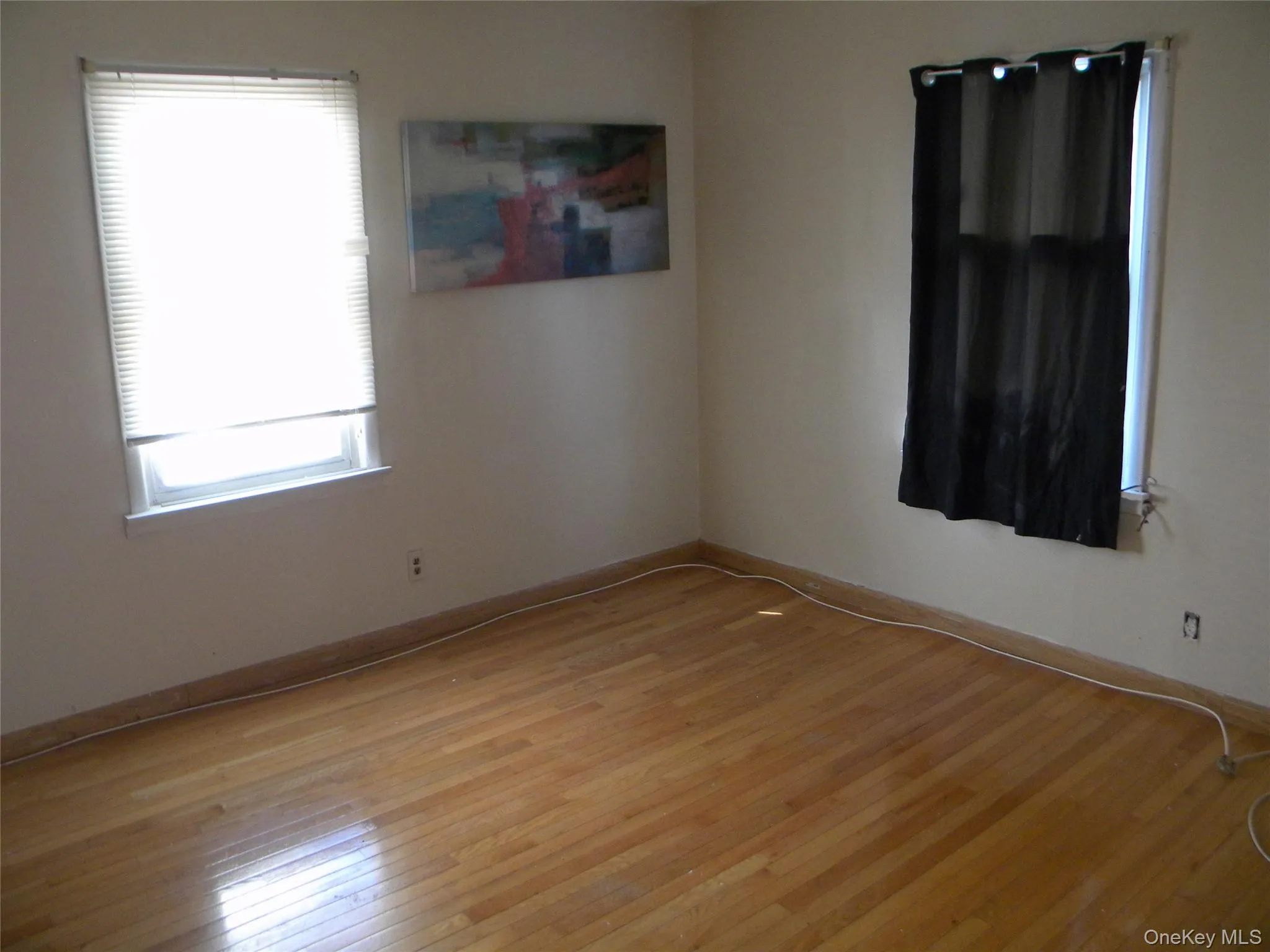 Hardwood flooring featuring a light finish, neutral wall tones, and two windows Hardwood flooring featuring a light finish, neutral wall tones, and two windows