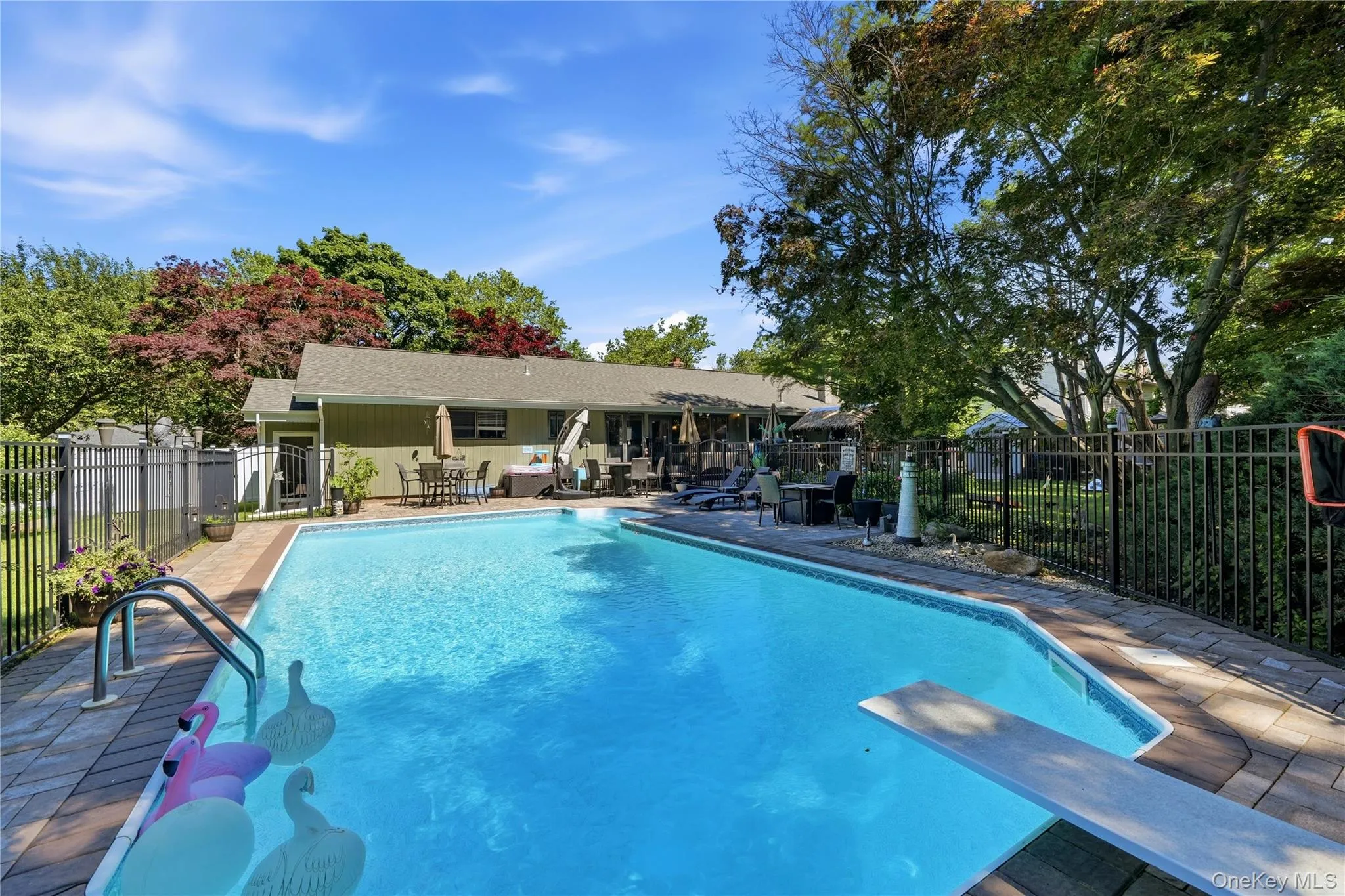 In-ground swimming pool with diving board and integrated steps, surrounded by paver patio In-ground swimming pool with diving board and integrated steps, surrounded by paver patio
