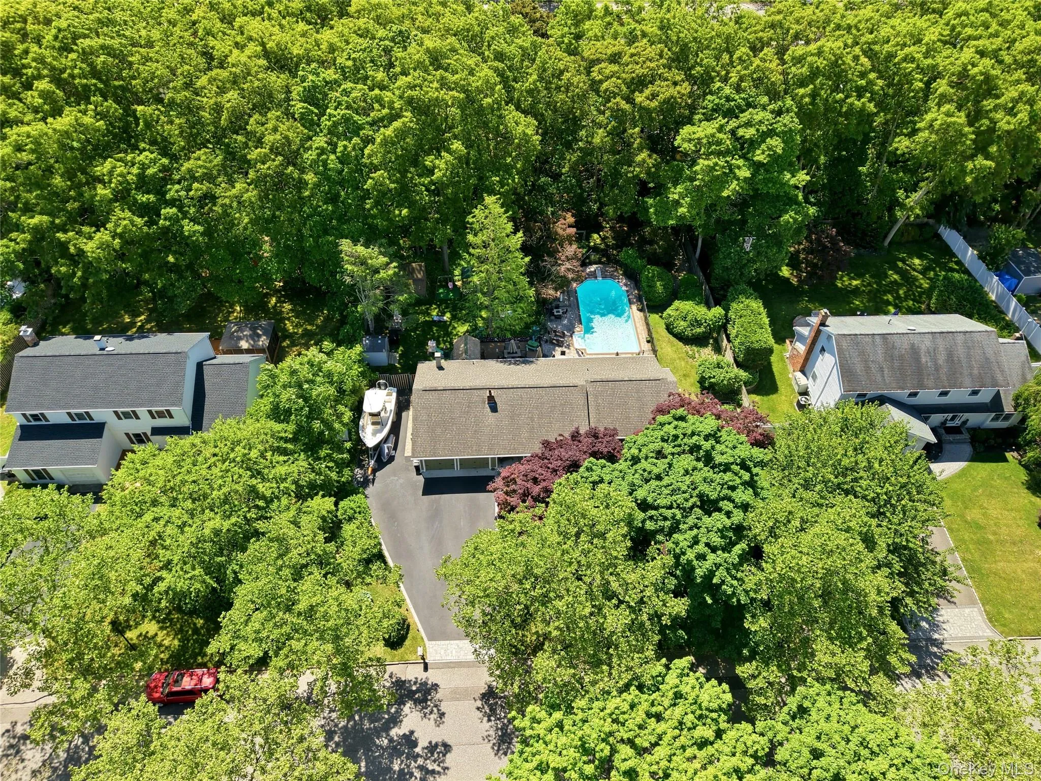 Aerial view showcasing a residential property with a private swimming pool, mature trees, and a paved driveway Aerial view showcasing a residential property with a private swimming pool, mature trees, and a paved driveway