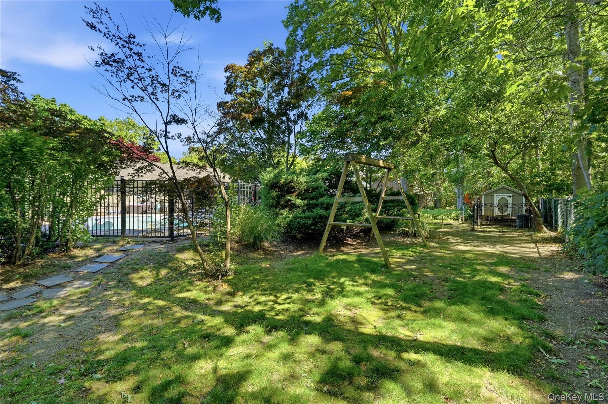 Expansive backyard featuring a manicured lawn, established trees, and a stone paver pathway Expansive backyard featuring a manicured lawn, established trees, and a stone paver pathway