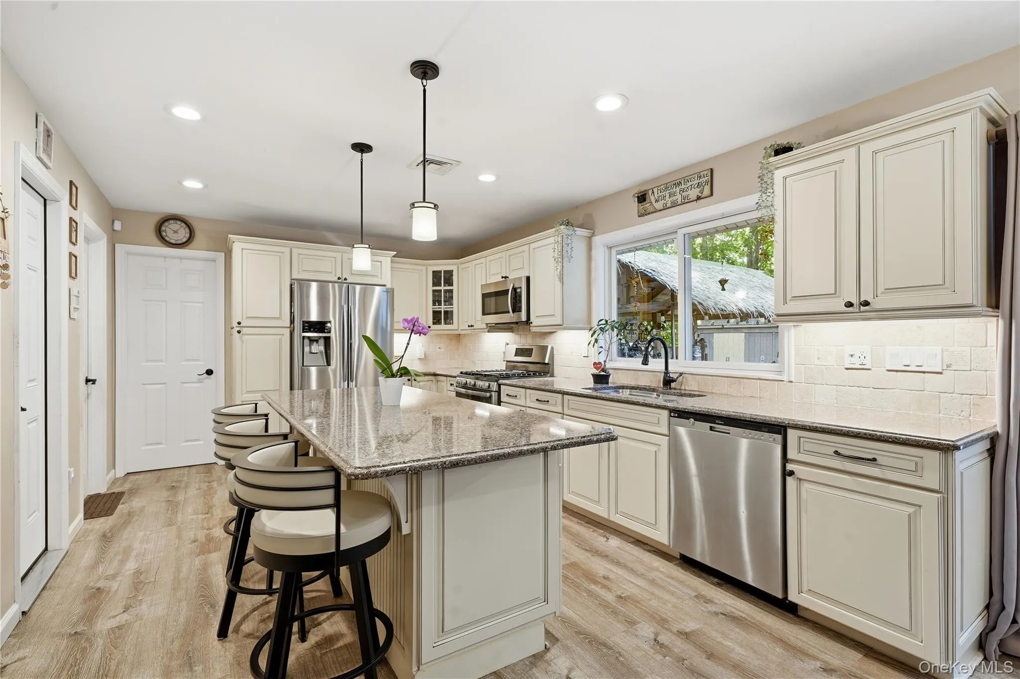 Spacious kitchen featuring an island with stone countertop, stainless steel appliances, light-toned cabinetry, wood-finish flooring, and recessed lighting Spacious kitchen featuring an island with stone countertop, stainless steel appliances, light-toned cabinetry, wood-finish flooring, and recessed lighting
