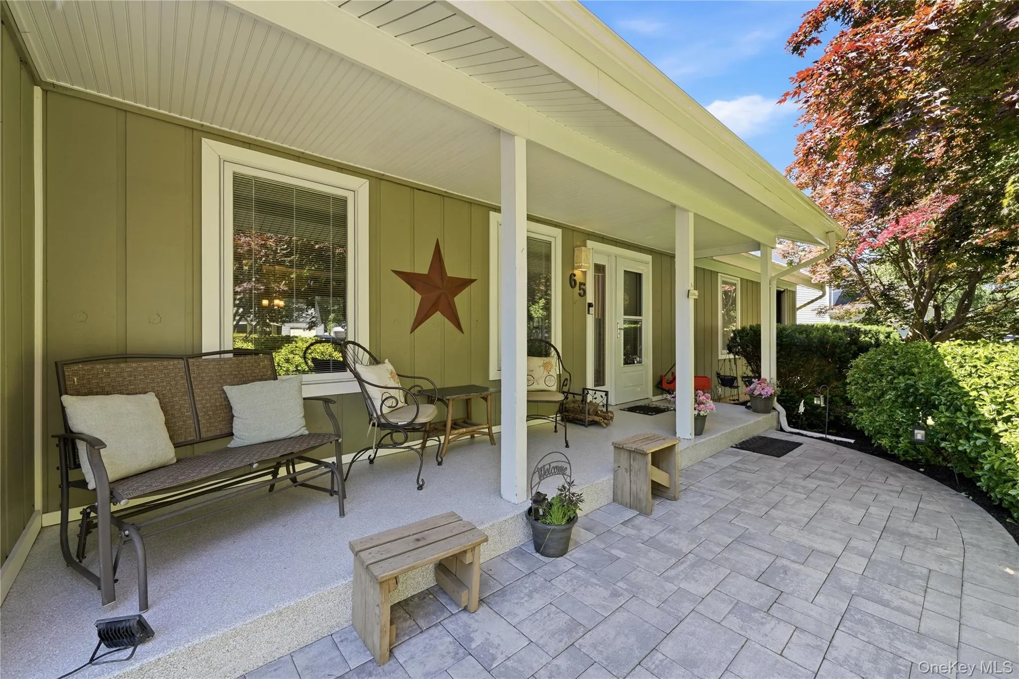 Expansive covered front porch featuring a textured concrete surface, white support columns, and a board and batten exterior Expansive covered front porch featuring a textured concrete surface, white support columns, and a board and batten exterior