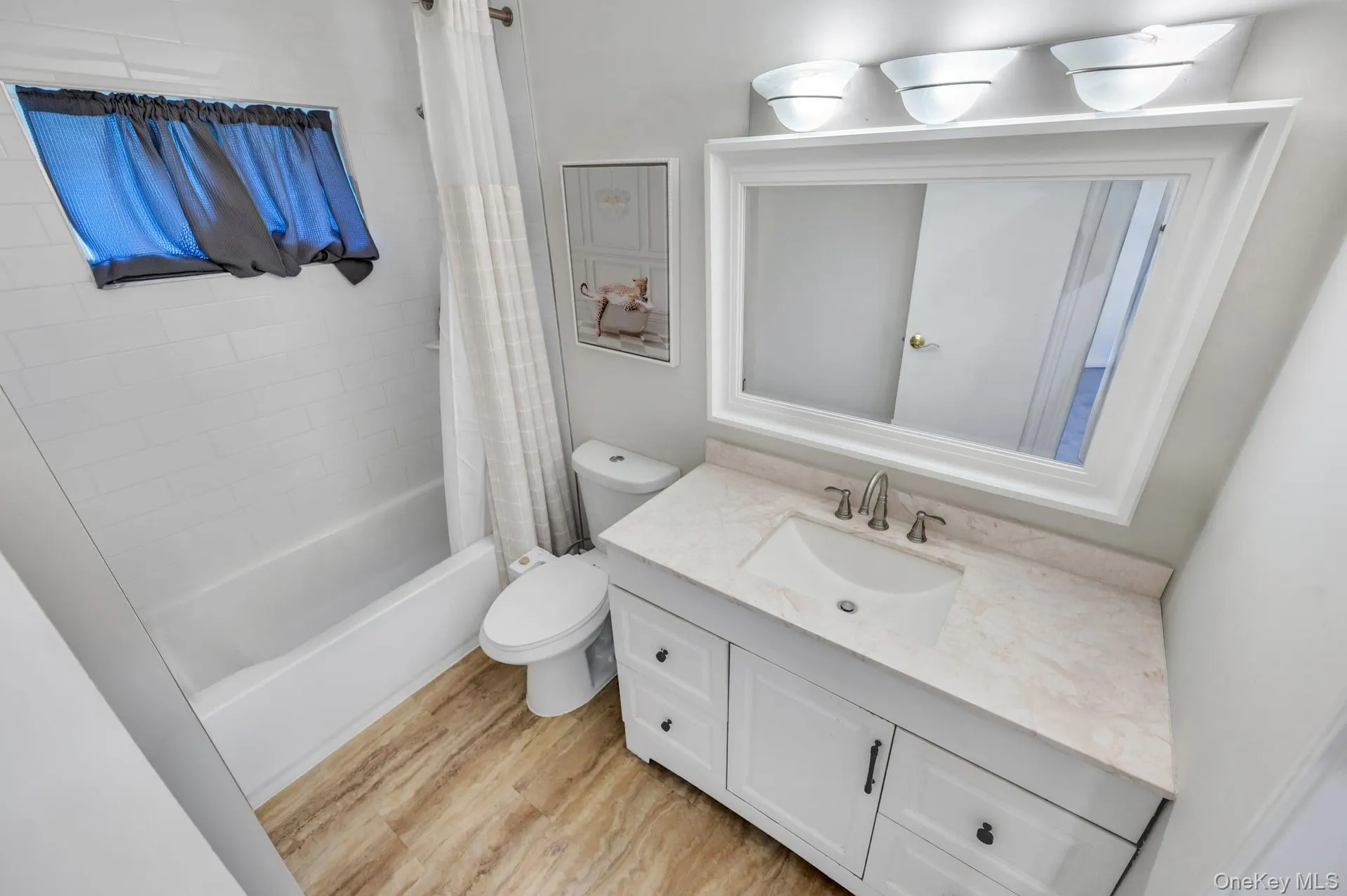 Bathroom featuring a single vanity with a solid surface countertop, an undermount sink, and a framed mirror Bathroom featuring a single vanity with a solid surface countertop, an undermount sink, and a framed mirror