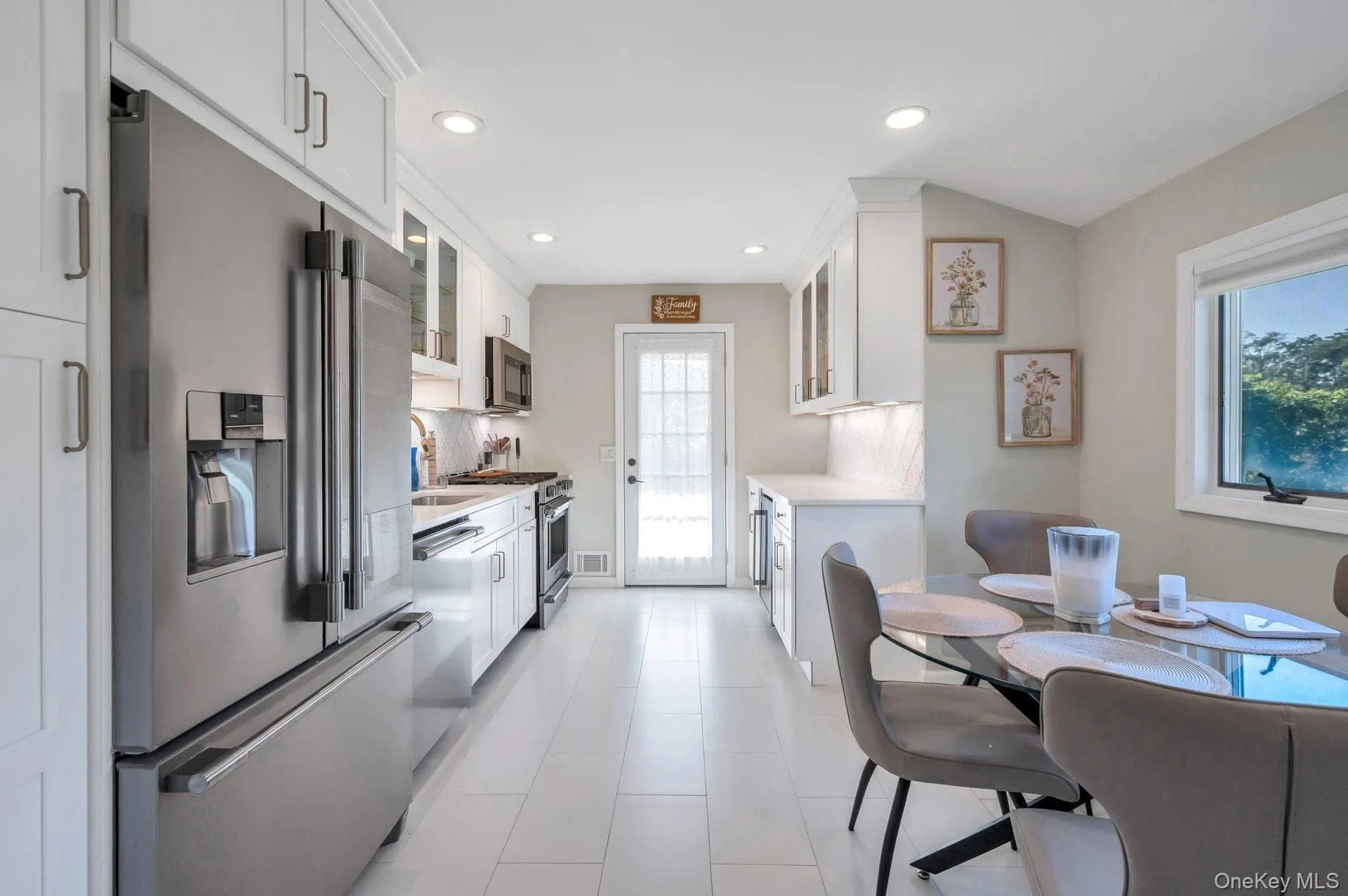 Kitchen featuring stainless steel appliances, white shaker cabinetry, recessed lighting, and a white tile floor Kitchen featuring stainless steel appliances, white shaker cabinetry, recessed lighting, and a white tile floor