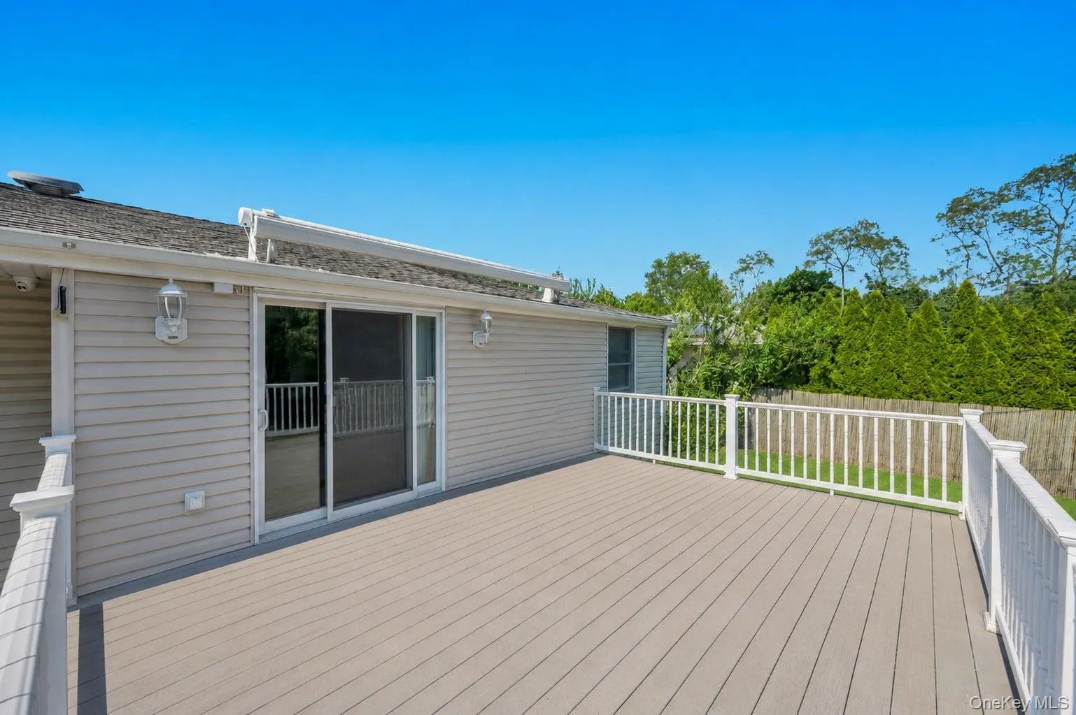 Expansive composite deck featuring white railing, providing generous outdoor living space Expansive composite deck featuring white railing, providing generous outdoor living space