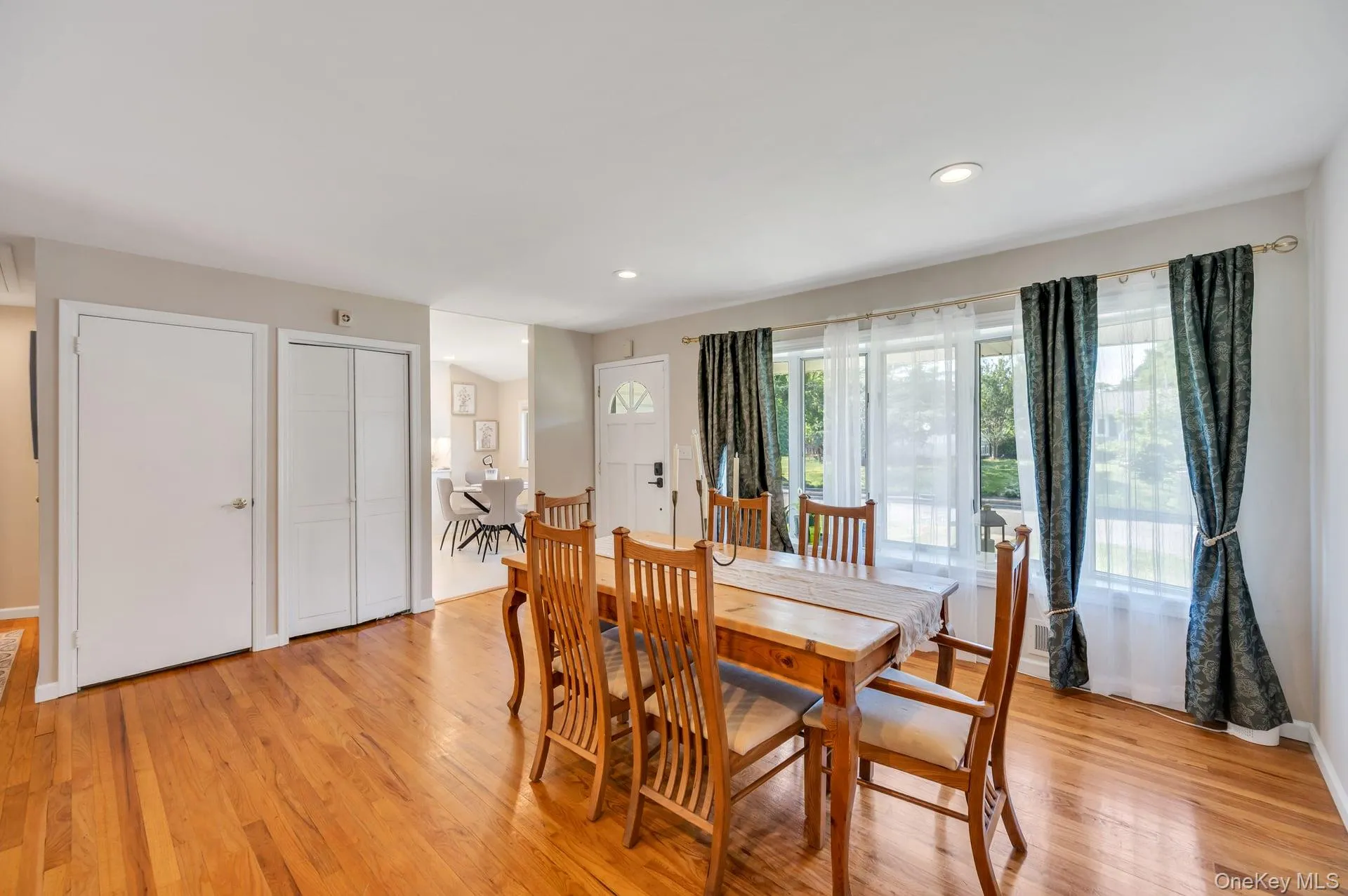 Dining area featuring wood-finish flooring, recessed lighting, white trim, and a prominent front entry door with a decorative glass insert Dining area featuring wood-finish flooring, recessed lighting, white trim, and a prominent front entry door with a decorative glass insert