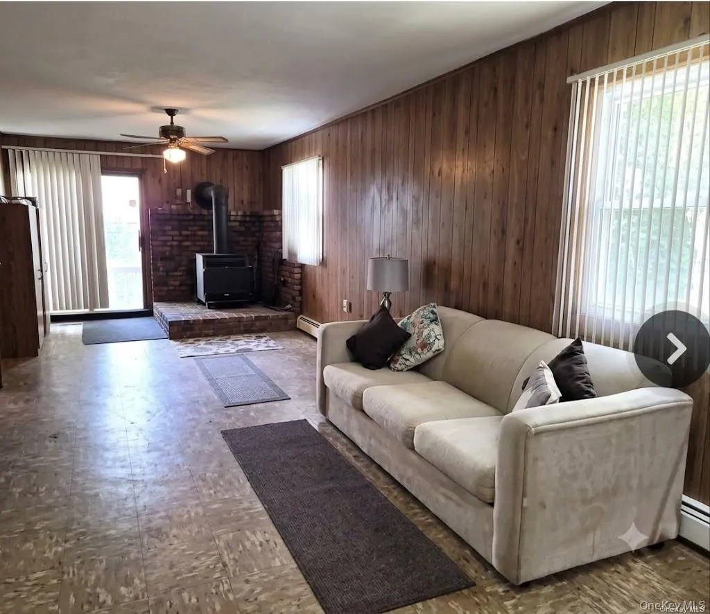 The Large Lower Level Living Room/Den Offers Two Outside Entrances - A Side Door & Back Sliding Doors, Two Large Windows For Natural Light, Wood Burning Stove With Brick Surround, Ceiling Fan, And Ample Room For Furniture. The Large Lower Level Living Room/Den Offers Two Outside Entrances - A Side Door & Back Sliding Doors, Two Large Windows For Natural Light, Wood Burning Stove With Brick Surround, Ceiling Fan, And Ample Room For Furniture.