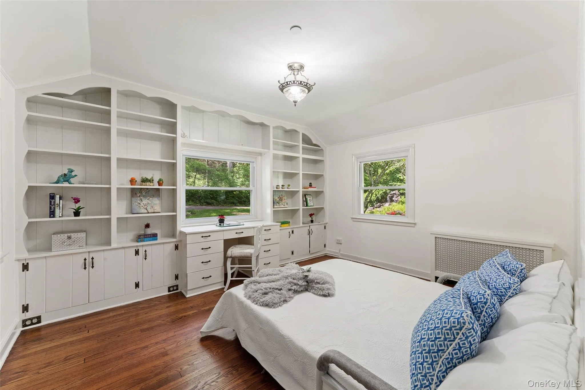 Another bedroom featuring extensive built-in white shelving and wood-finish flooring Another bedroom featuring extensive built-in white shelving and wood-finish flooring
