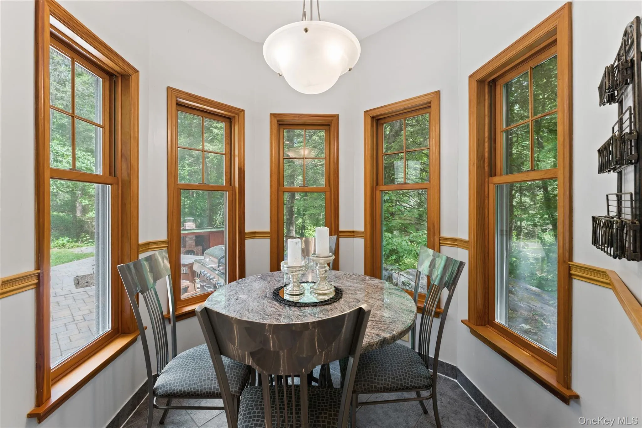 Breakfast nook featuring a bay window design with wood trim, a contemporary pendant light fixture and dark tile flooring Breakfast nook featuring a bay window design with wood trim, a contemporary pendant light fixture and dark tile flooring