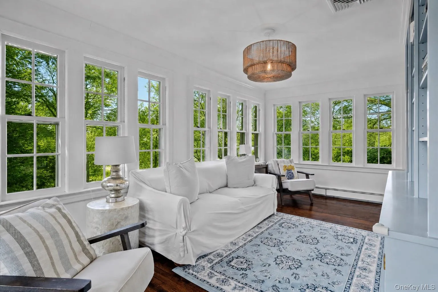 Family room featuring abundant windows with natural light, wood-finish flooring, a textured ceiling fixture, and built-in shelving Family room featuring abundant windows with natural light, wood-finish flooring, a textured ceiling fixture, and built-in shelving