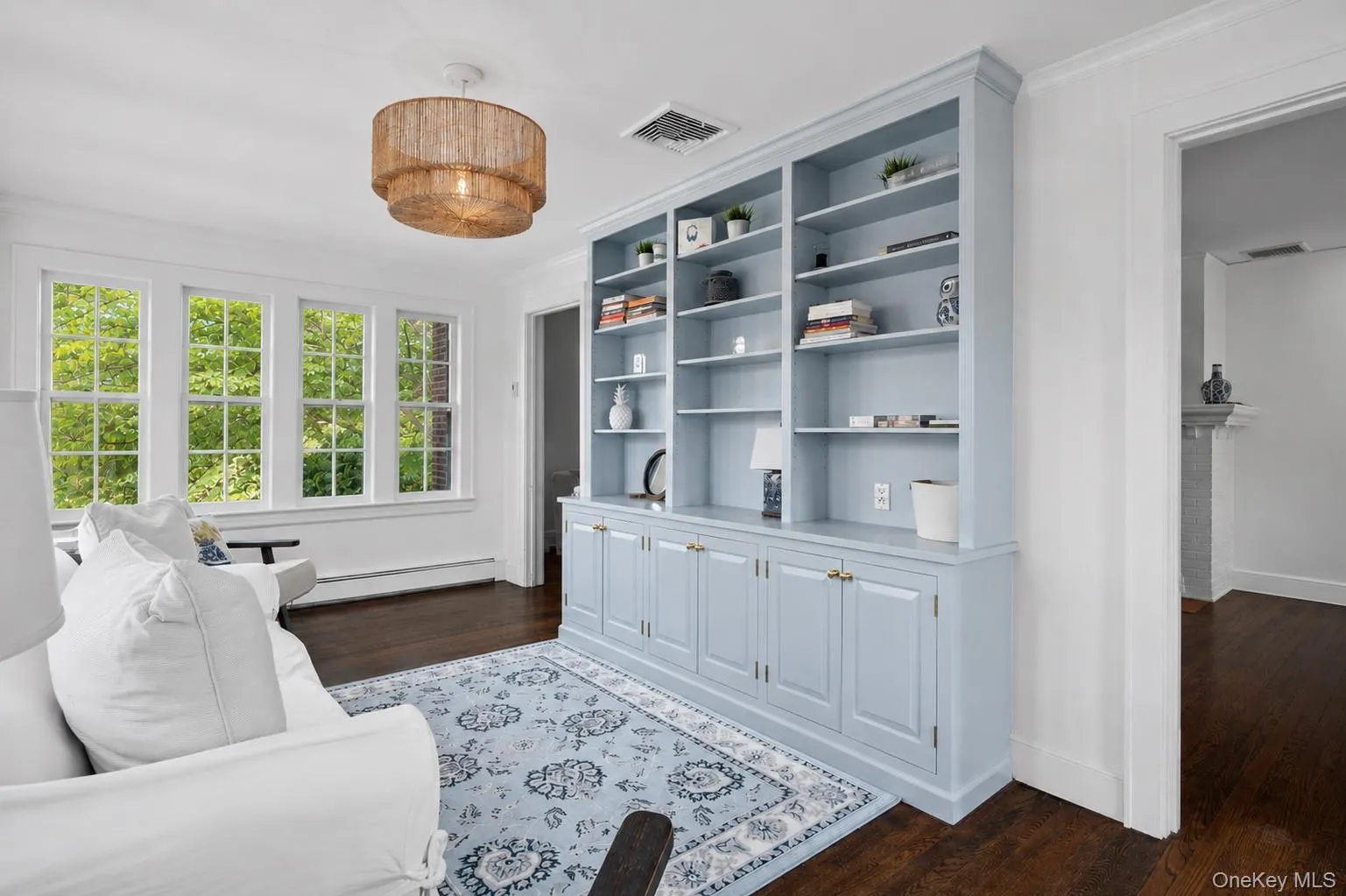 Family room featuring abundant windows with natural light, wood-finish flooring, a textured ceiling fixture, and built-in shelving Family room featuring abundant windows with natural light, wood-finish flooring, a textured ceiling fixture, and built-in shelving