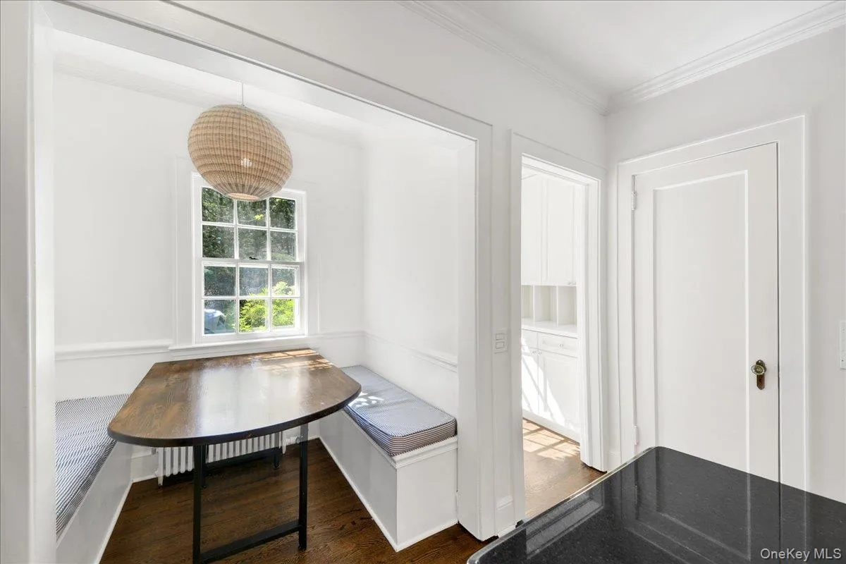 Built-in breakfast nook with a wood-finish table, a woven pendant light fixture, and a double-hung window Built-in breakfast nook with a wood-finish table, a woven pendant light fixture, and a double-hung window