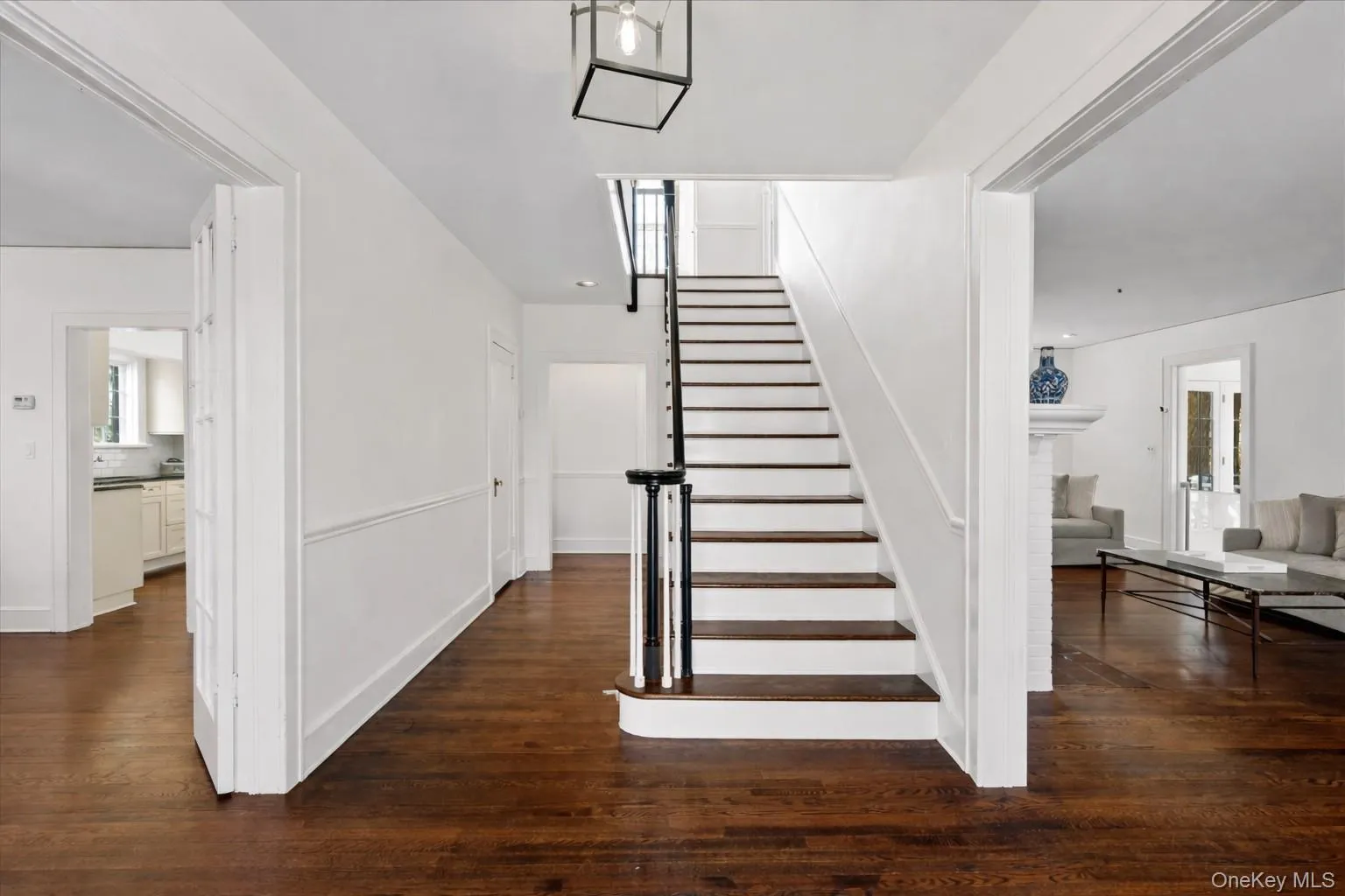 Foyer featuring a grand staircase with dark wood treads and white risers, framed by an open balustrade Foyer featuring a grand staircase with dark wood treads and white risers, framed by an open balustrade