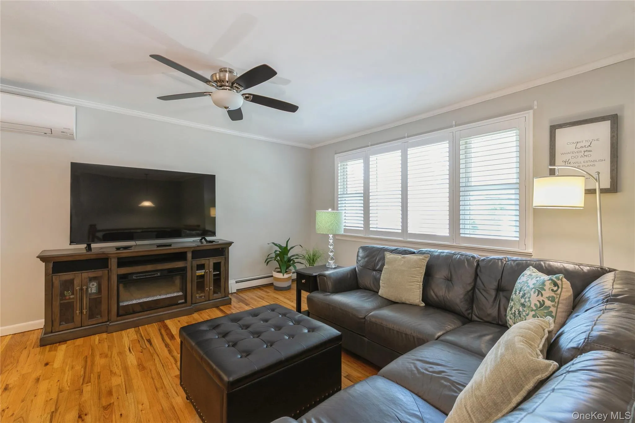 Living area featuring wood-finish flooring, a ceiling fan with light, and light gray walls Living area featuring wood-finish flooring, a ceiling fan with light, and light gray walls
