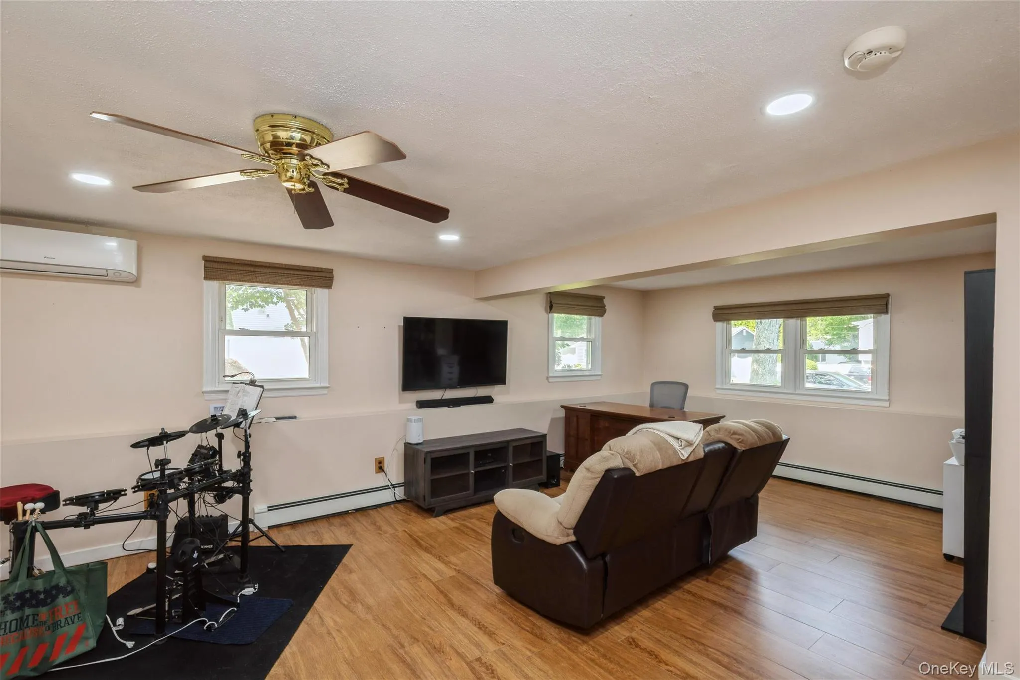 Spacious room featuring laminated flooring, recessed lighting, and multiple windows Spacious room featuring laminated flooring, recessed lighting, and multiple windows