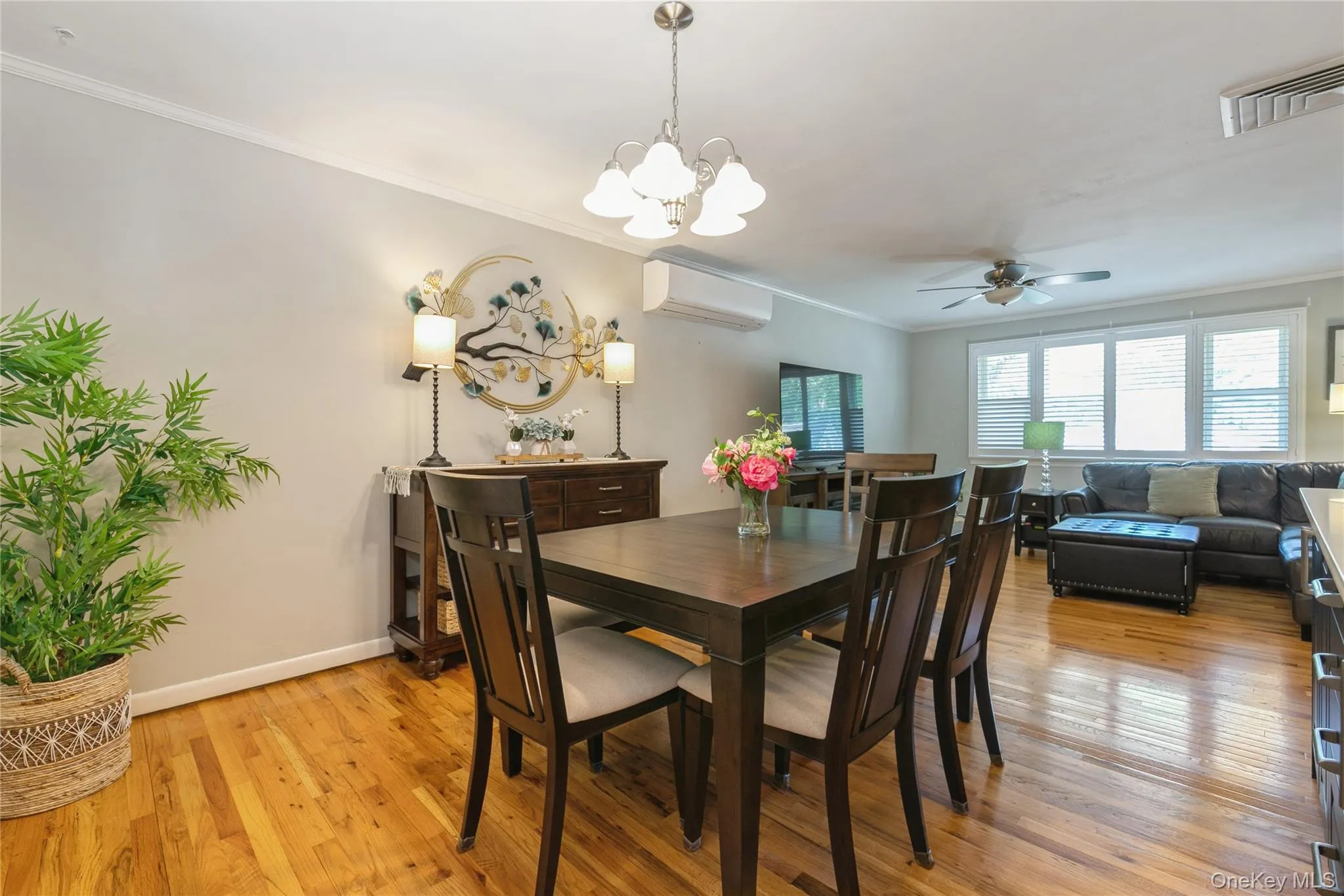 Open-concept dining area featuring wood-finish flooring, crown molding, and a contemporary chandelier Open-concept dining area featuring wood-finish flooring, crown molding, and a contemporary chandelier