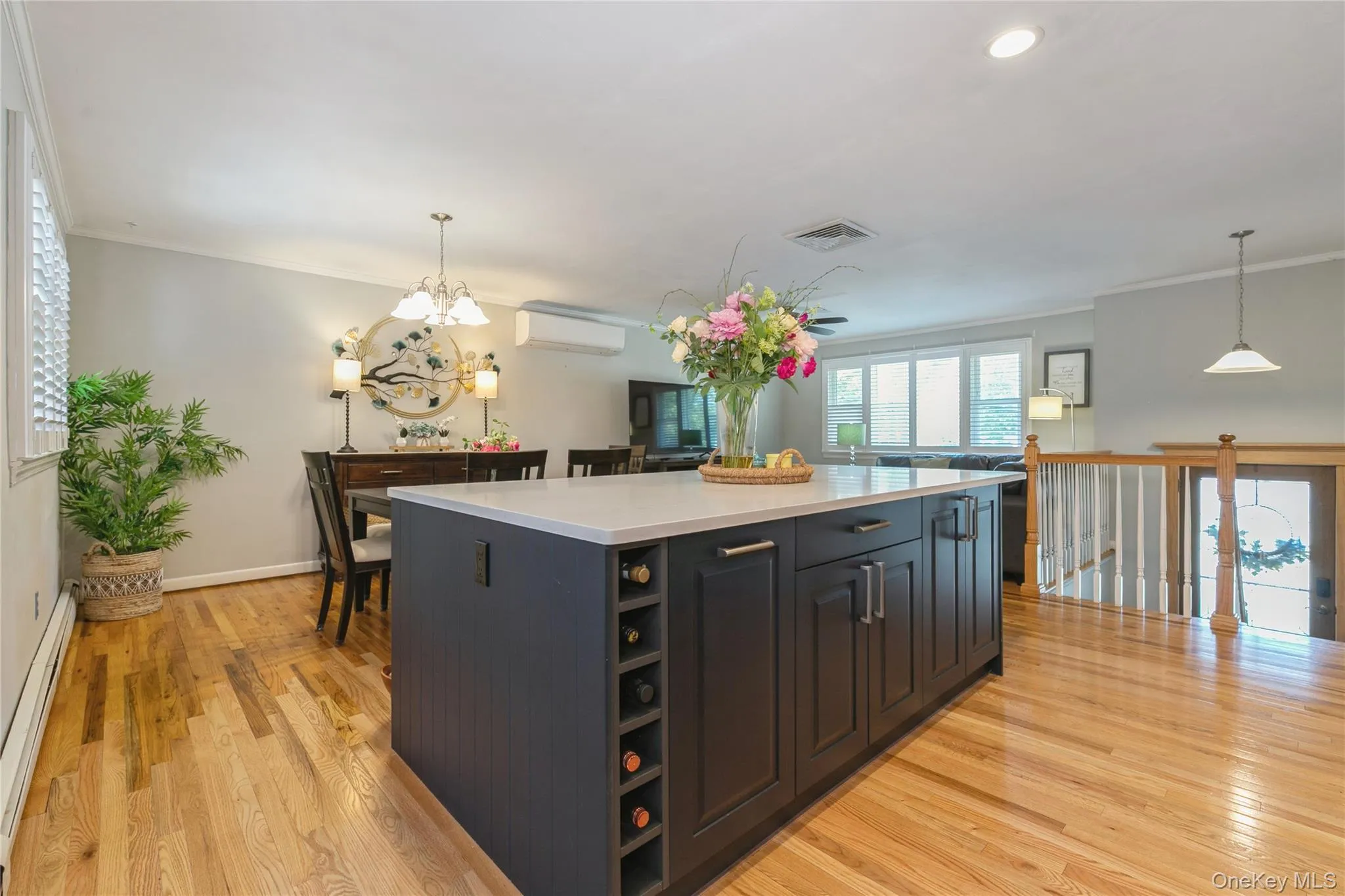 Kitchen island featuring dark cabinetry, integrated wine storage, and a light-toned countertop Kitchen island featuring dark cabinetry, integrated wine storage, and a light-toned countertop