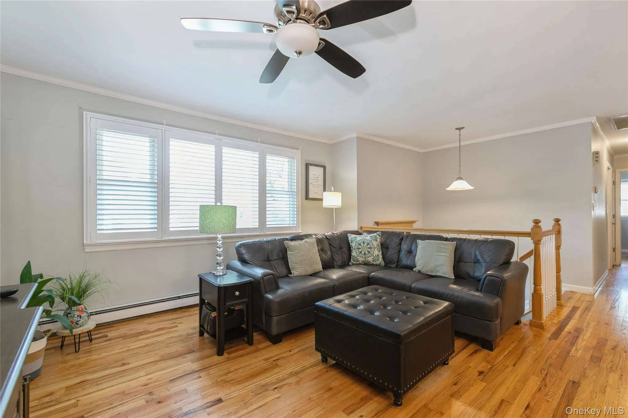 Living area featuring wood-finish flooring, a multi-pane window with horizontal blinds, and a ceiling fan with integrated lighting Living area featuring wood-finish flooring, a multi-pane window with horizontal blinds, and a ceiling fan with integrated lighting