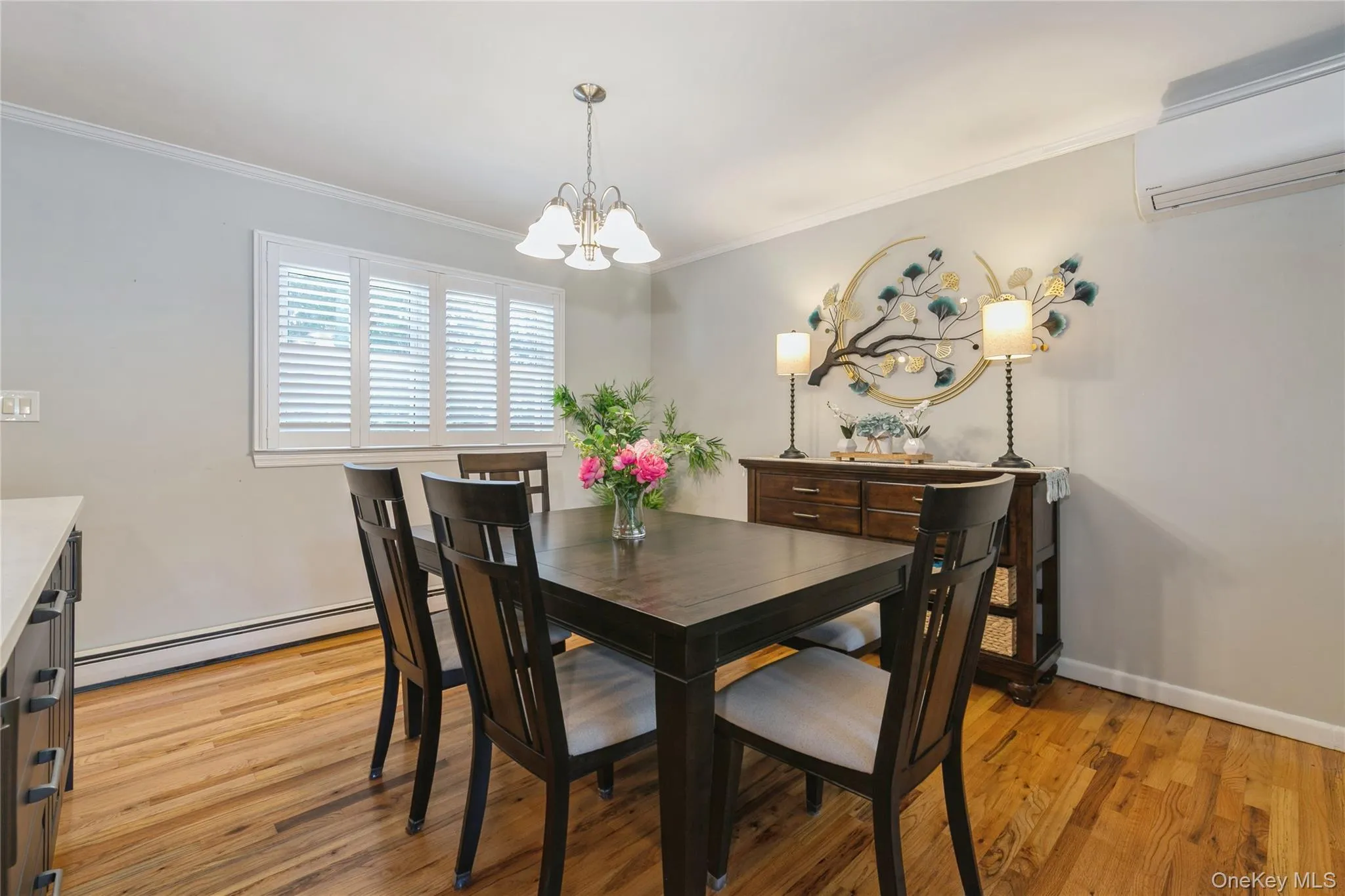 Dining area with wood-finish flooring, crown molding, and a chandelier Dining area with wood-finish flooring, crown molding, and a chandelier